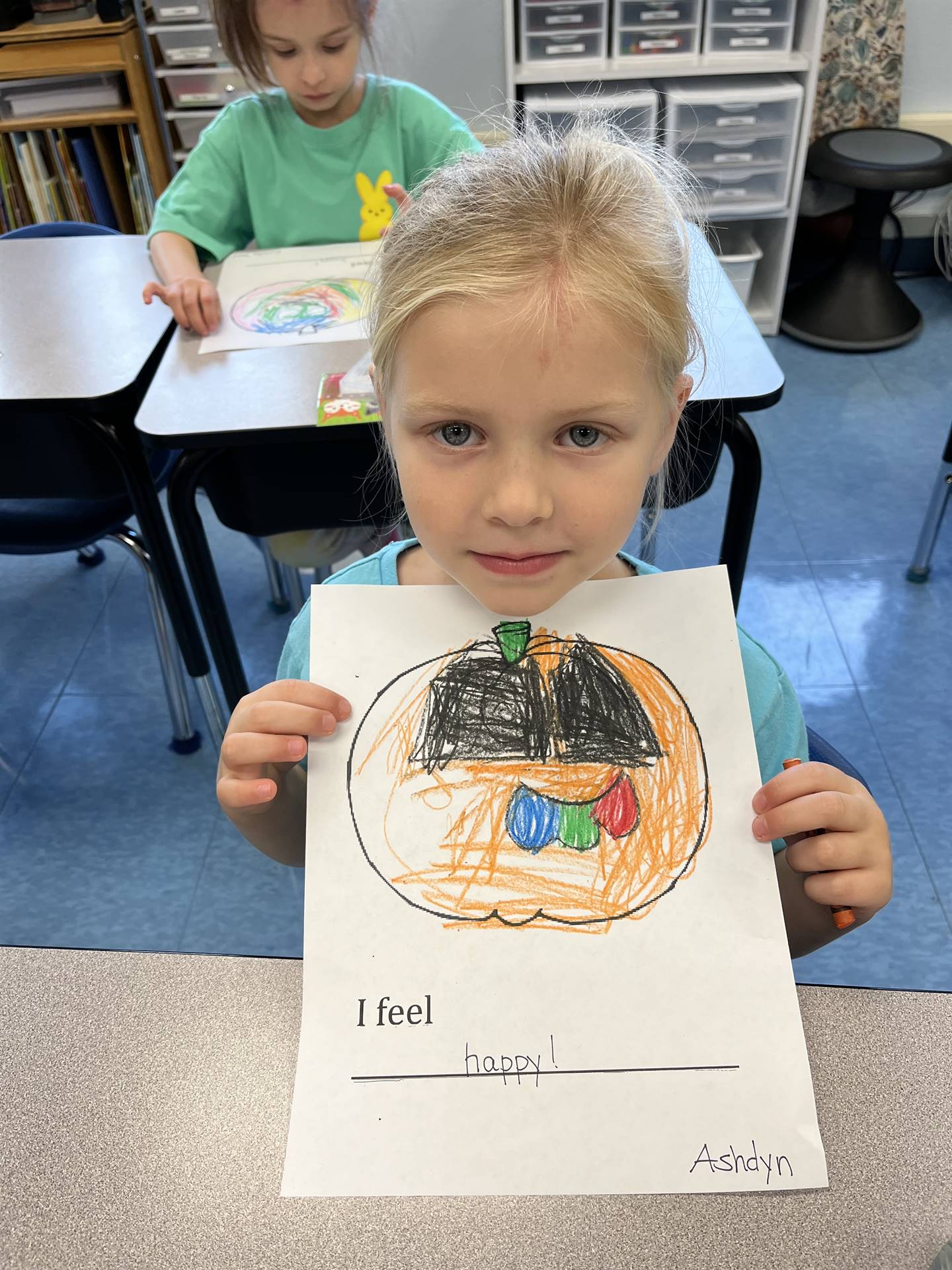 student holding a colored pumpkin with an emotion face