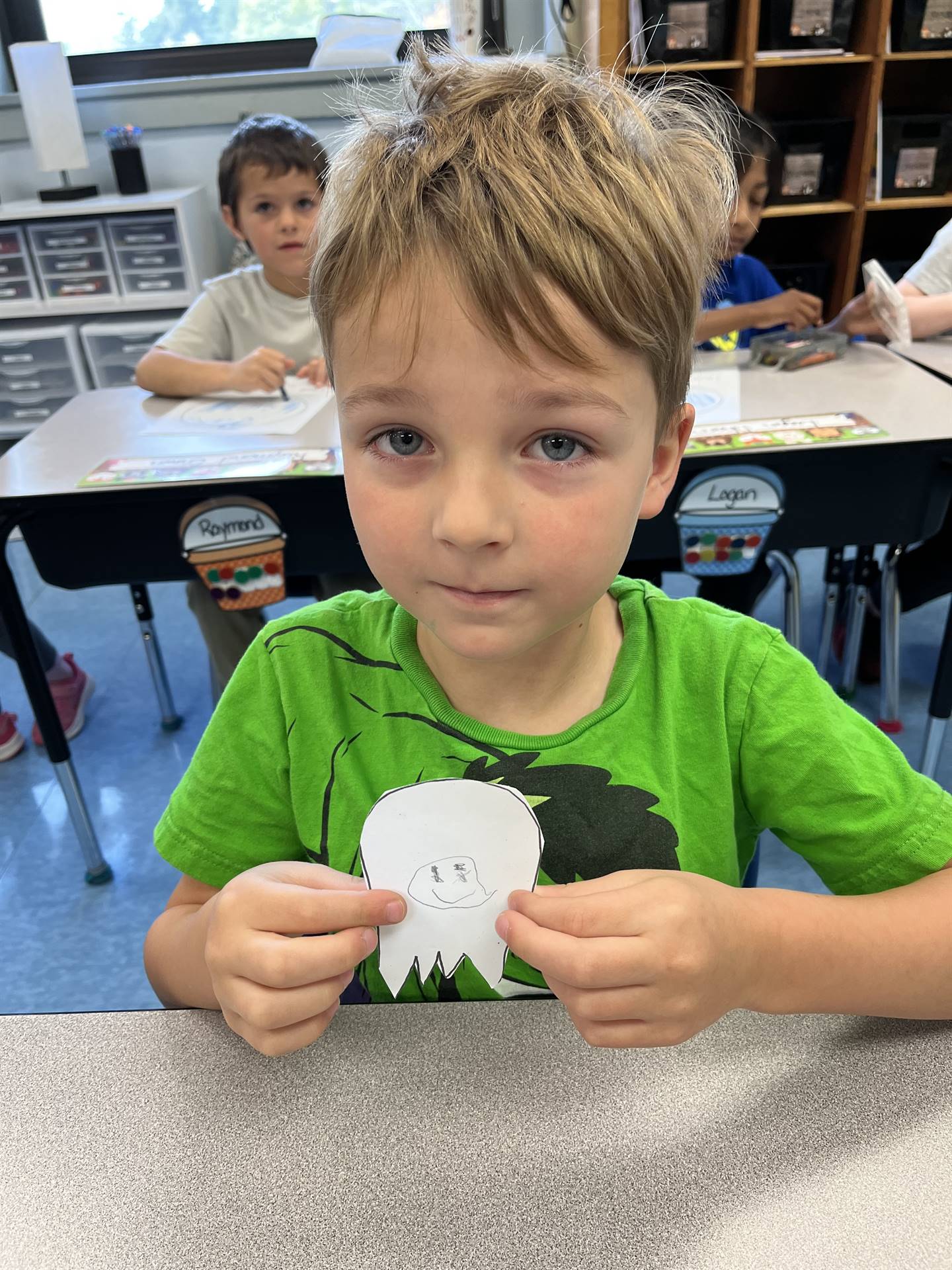 student holding a paper ghost with a drawn emotion on it.