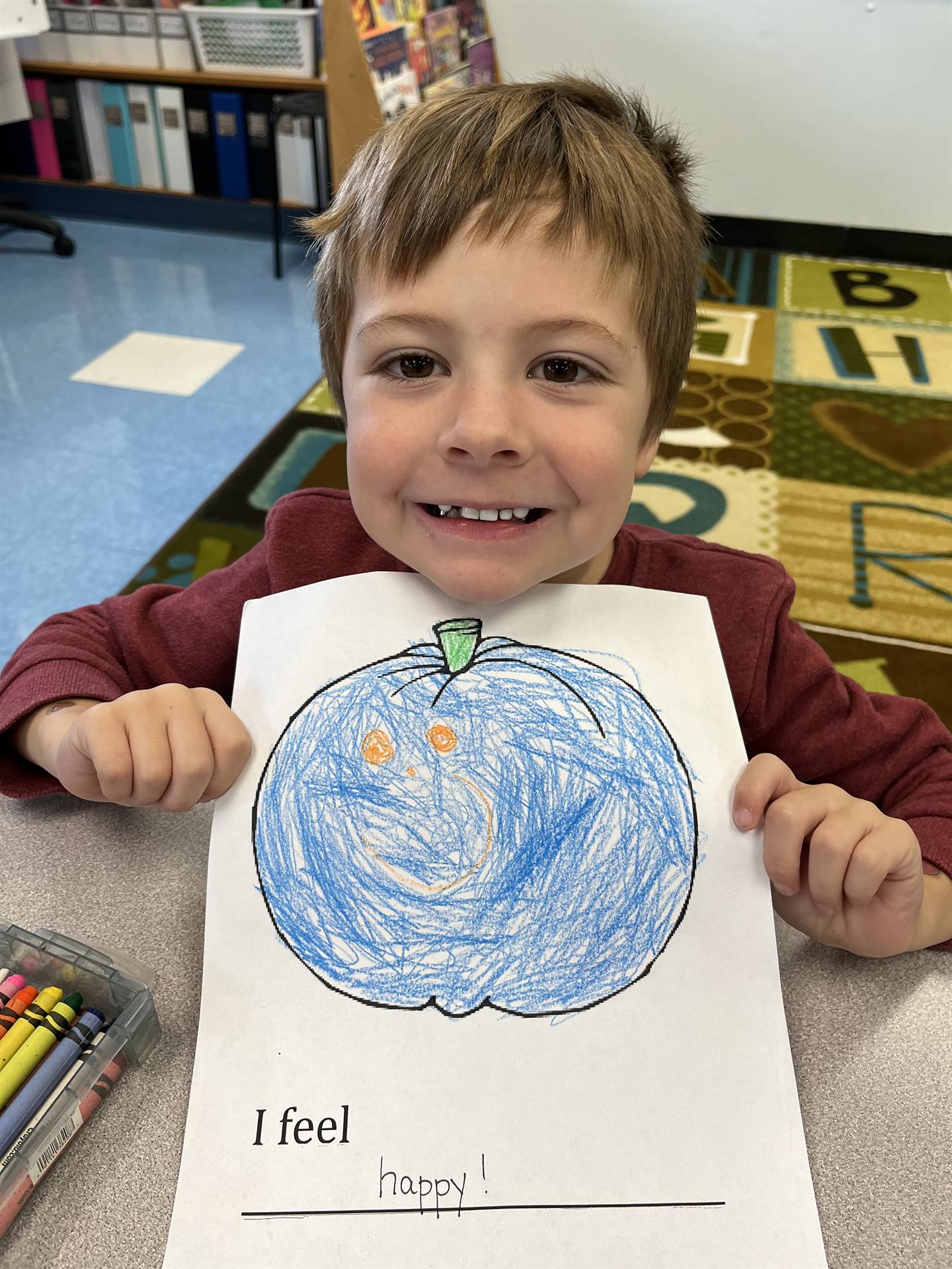 student holding a blue colored pumpkin