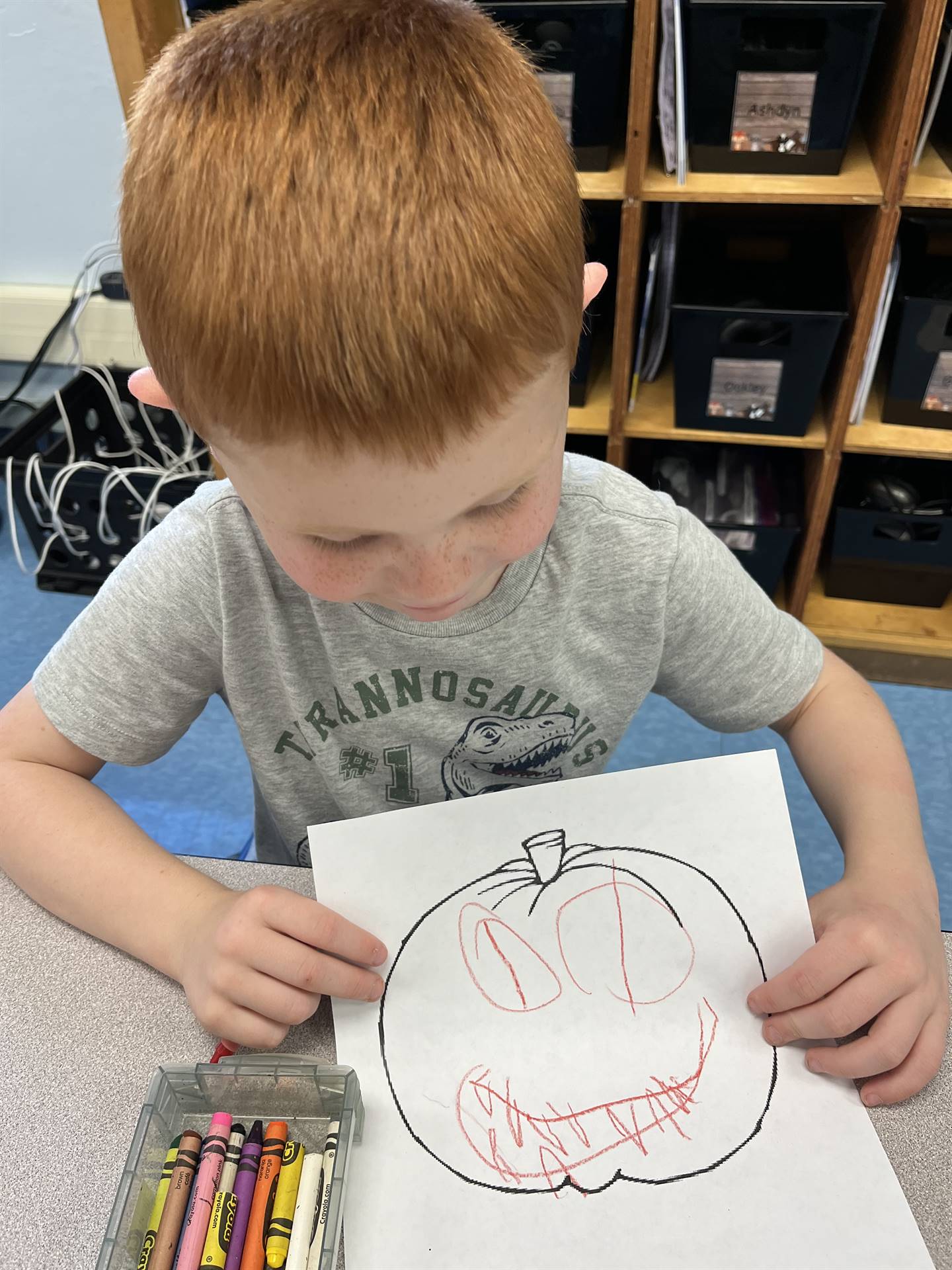 student holding a colored pumpkin with a drawn emotion face