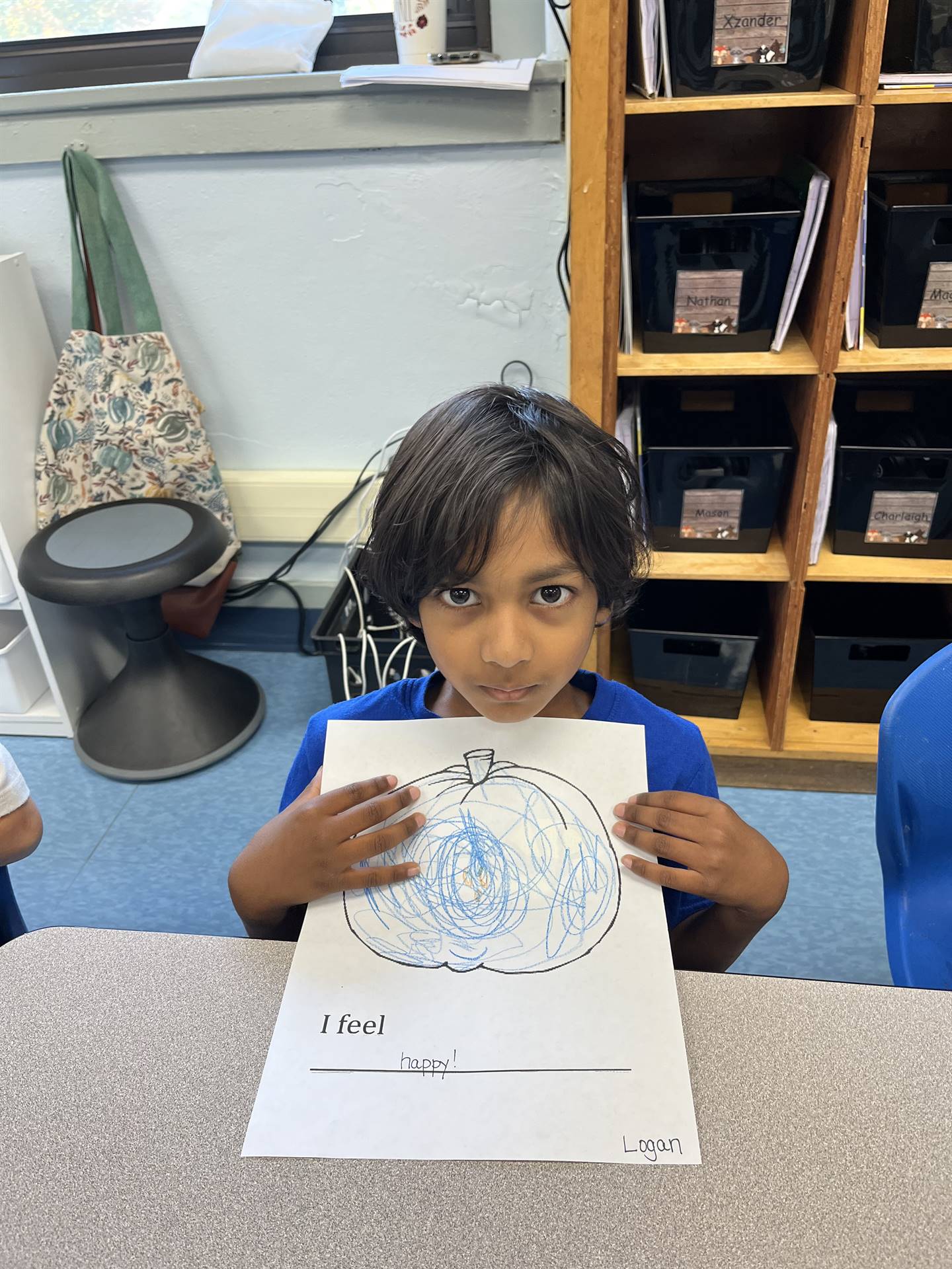 student holding a blue colored pumpkin