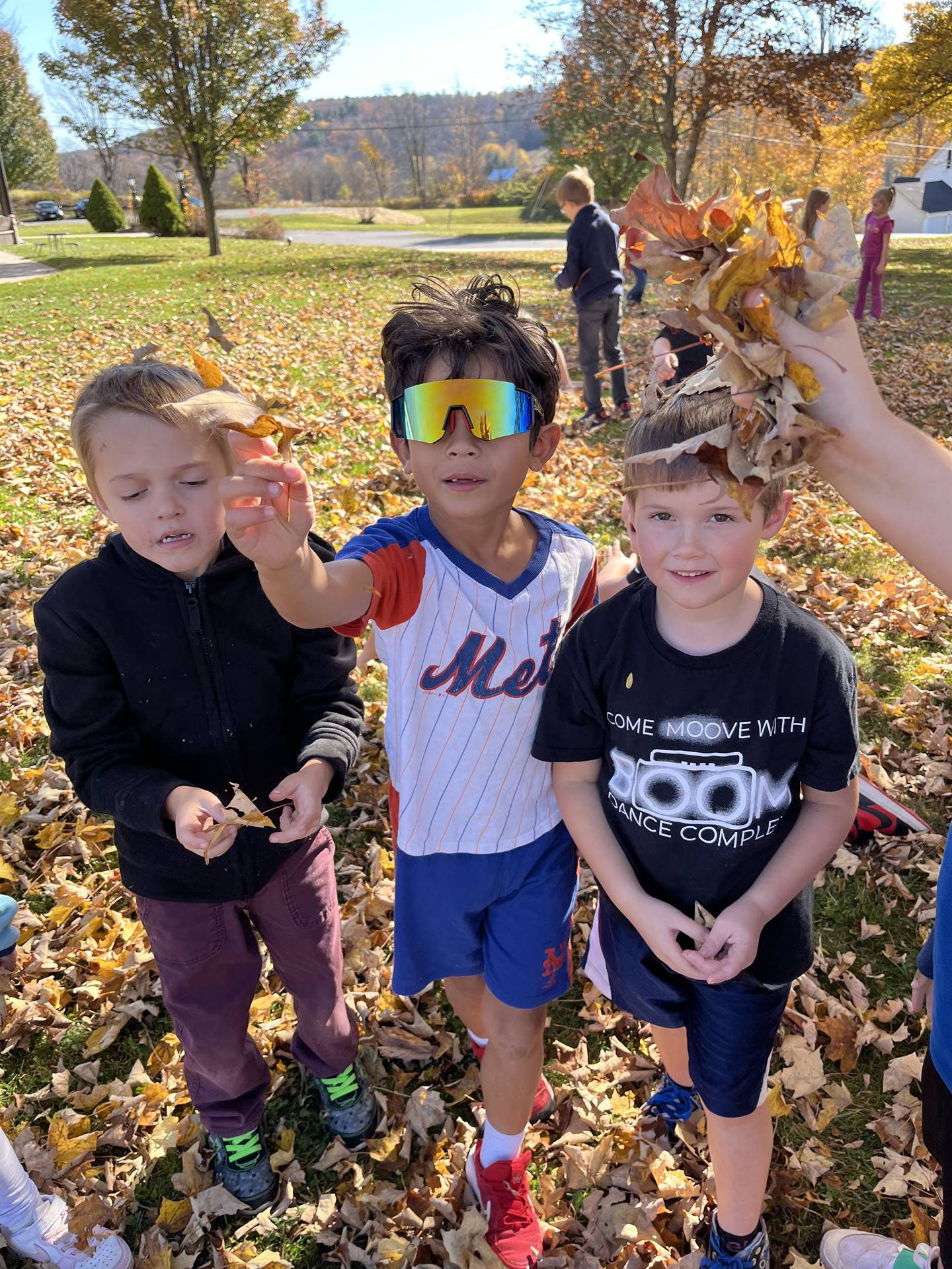 3 kids outside playing with leaves