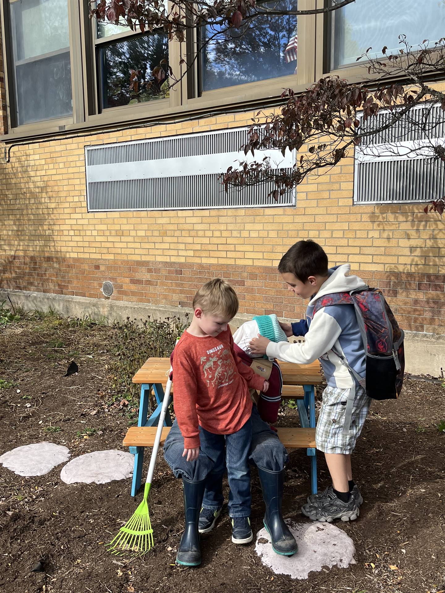 2 kids checking out a scarecrow on a bench.