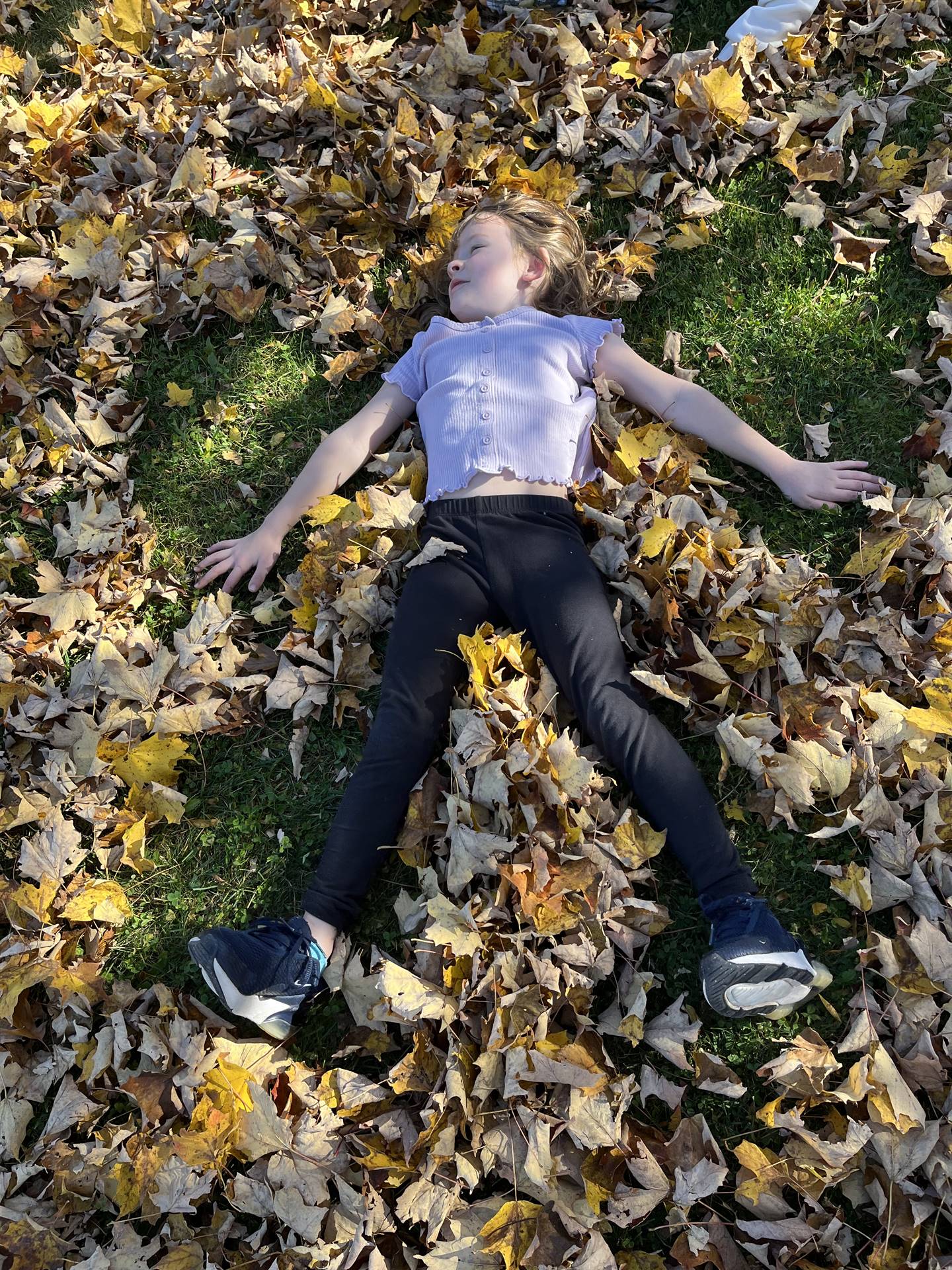 a kid laying on ground in the leaves