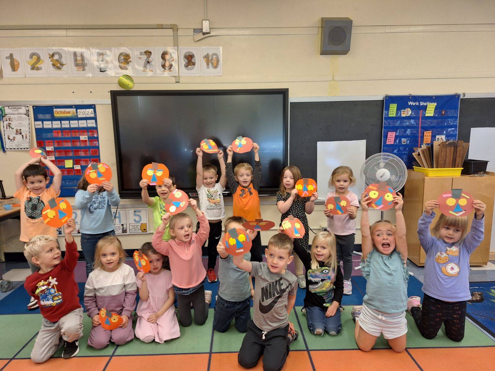 students holding up paper orange jackolanterns 