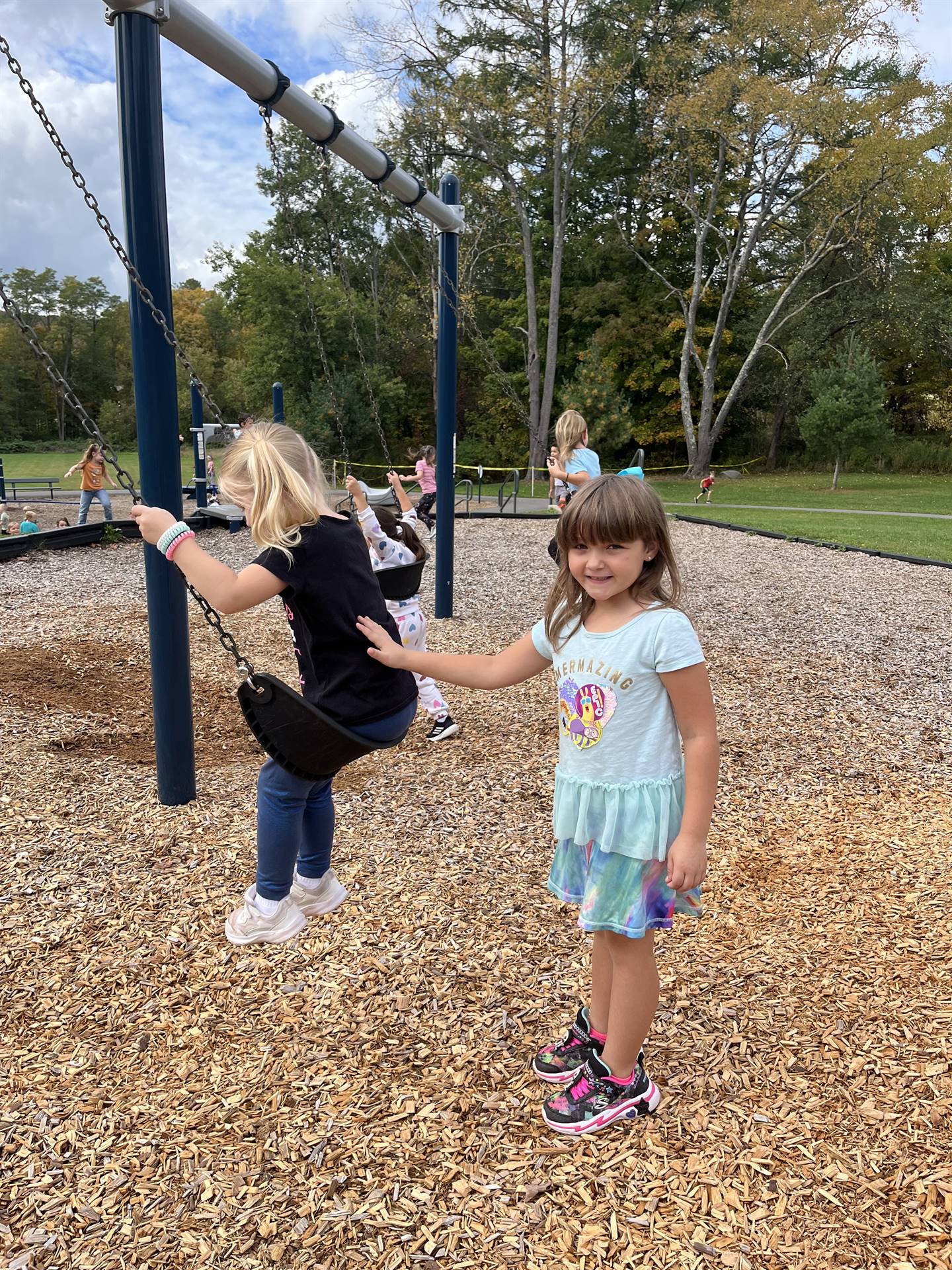 student pushing another on a swing