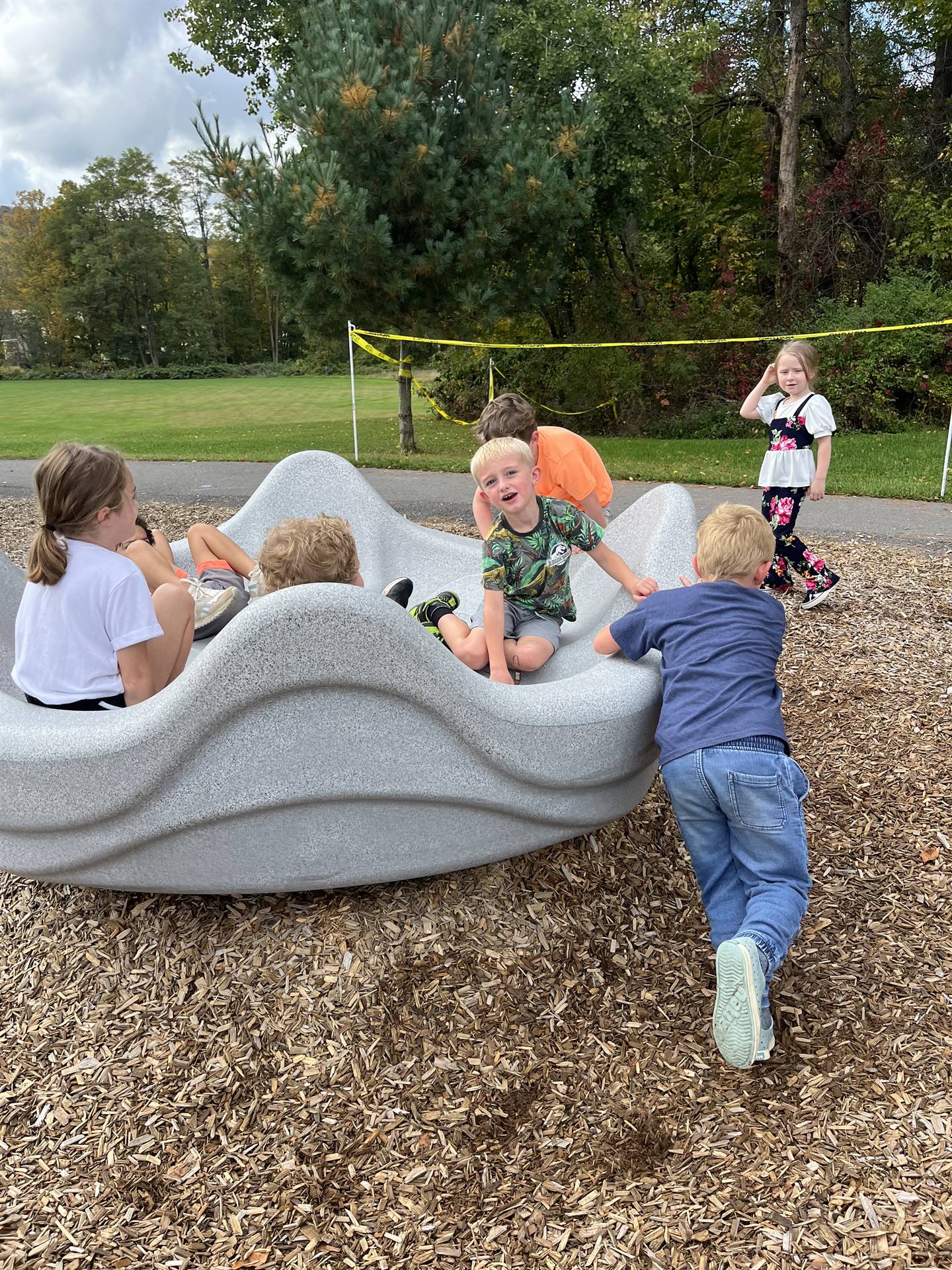 students pushing others in a giant twirling playground toy.