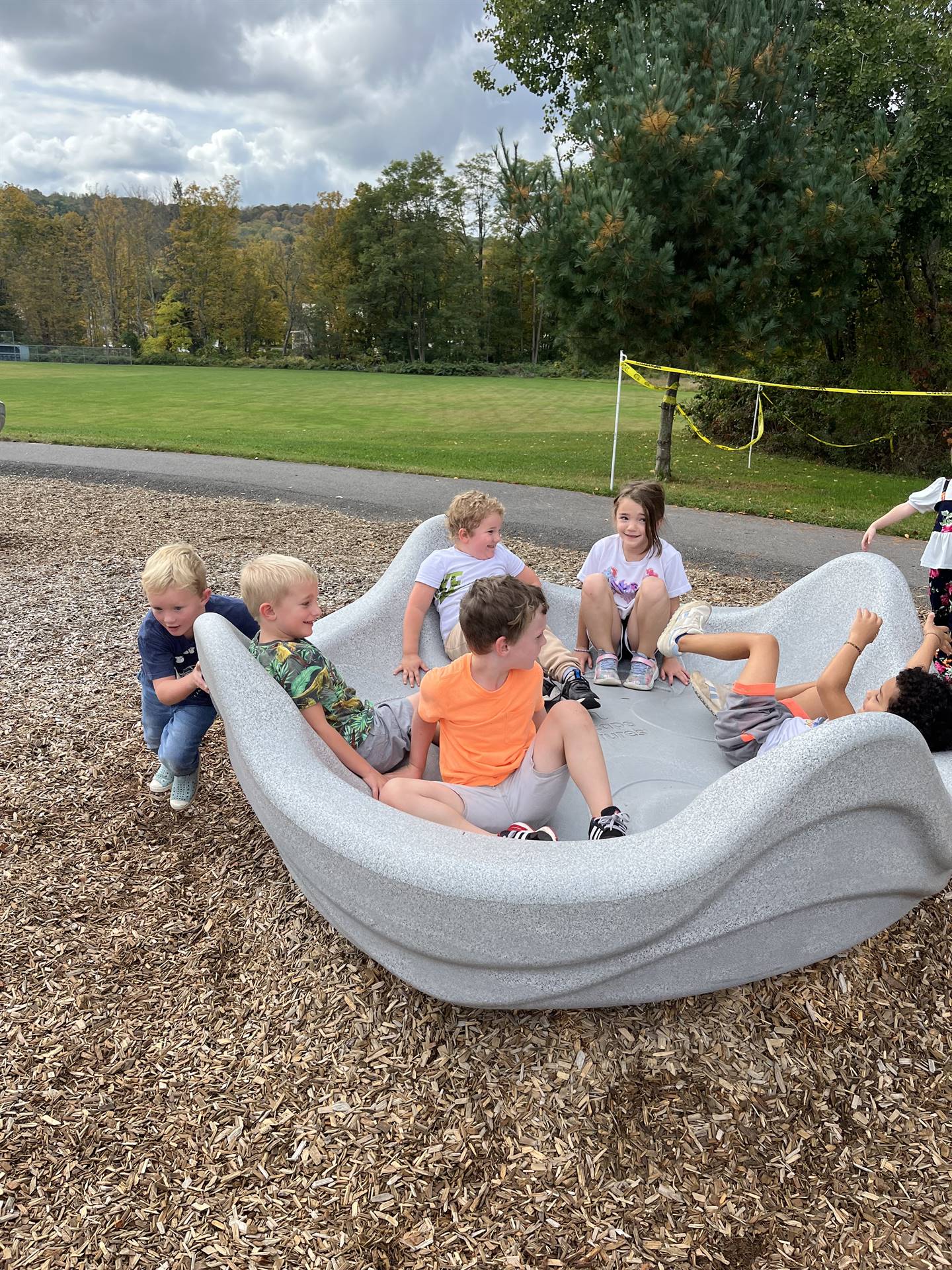 students pushing others in a giant twirling playground toy.