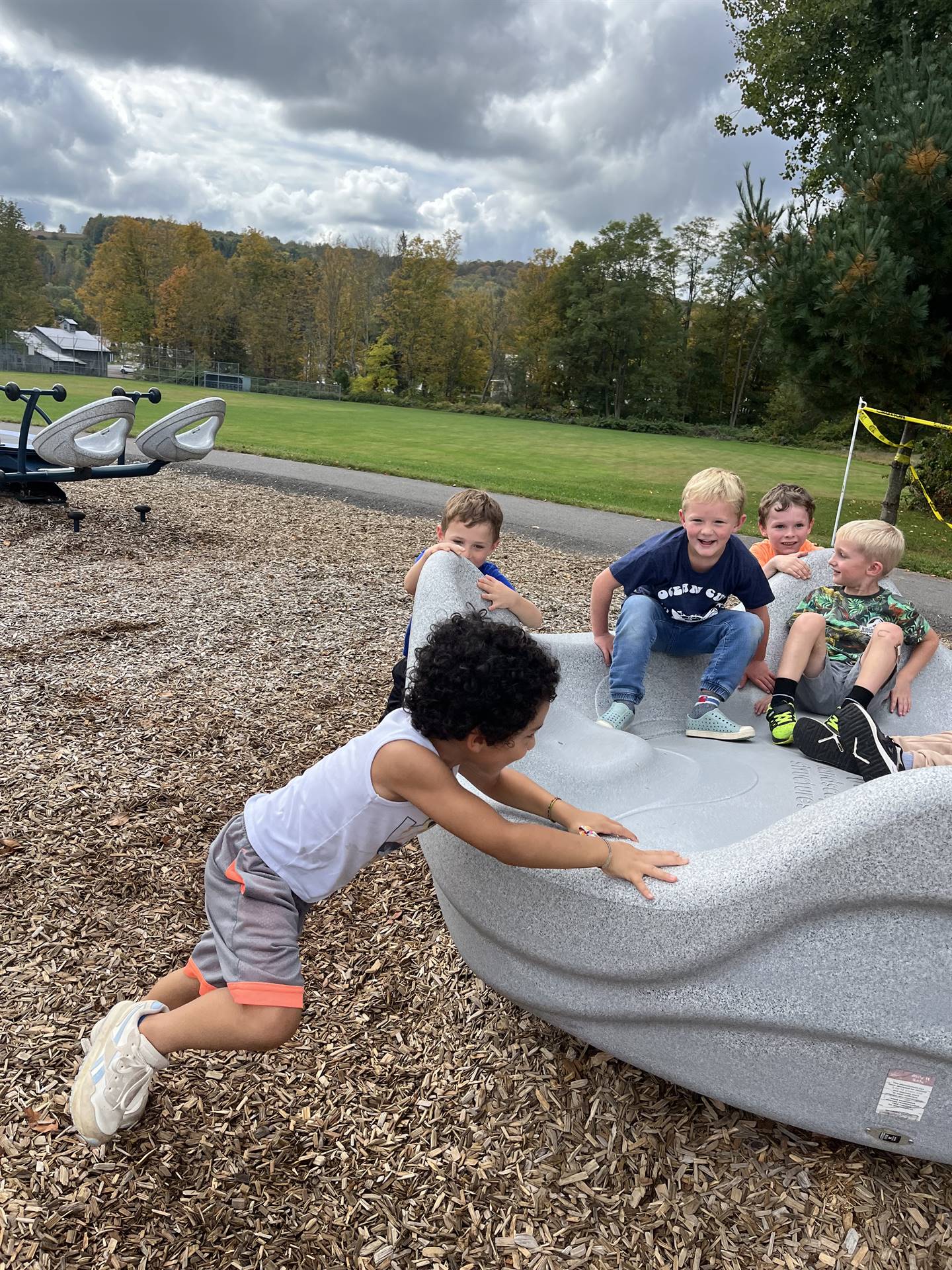 students pushing others in a giant twirling playground toy.