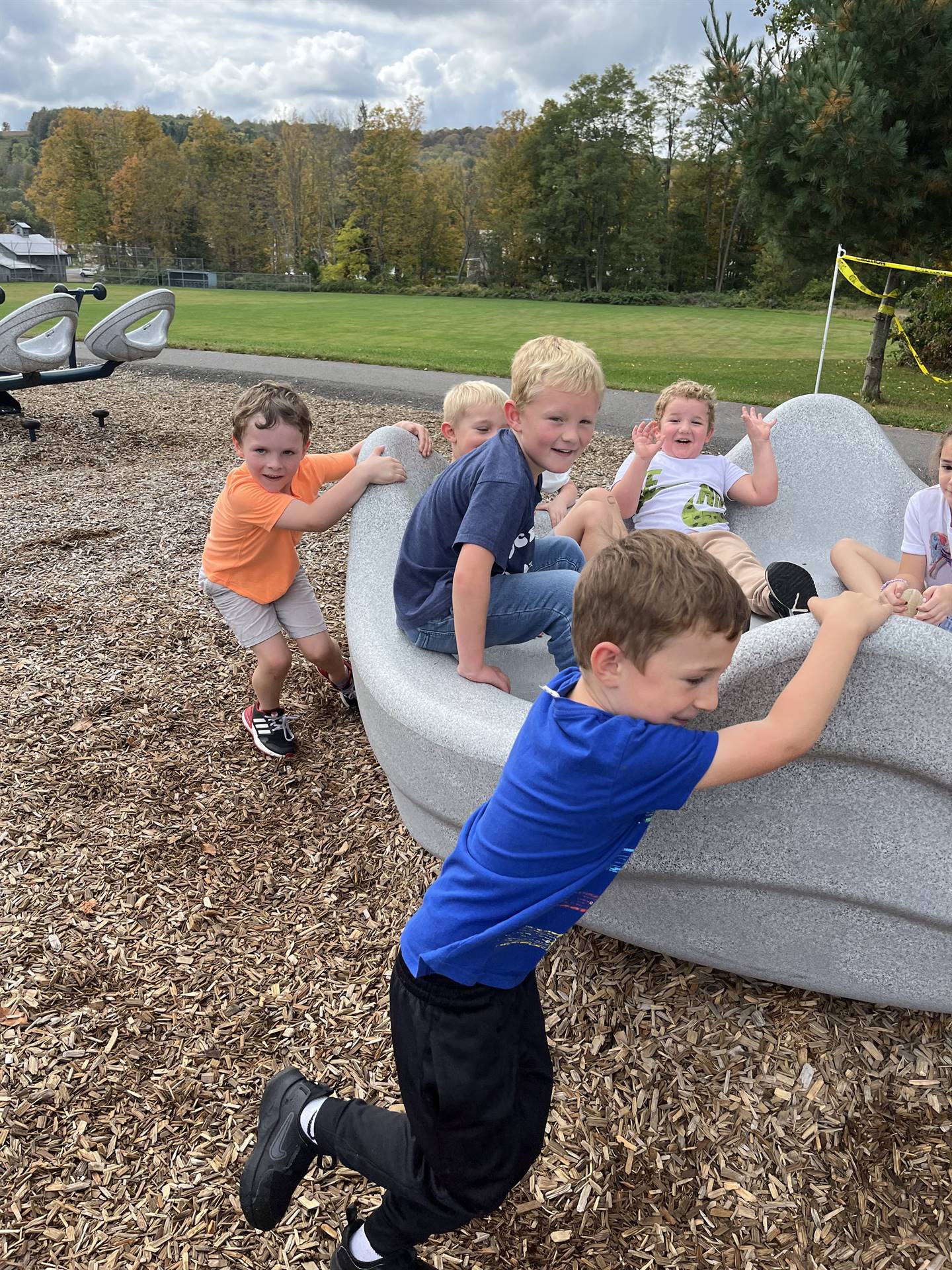 students pushing others in a giant twirling playground toy.