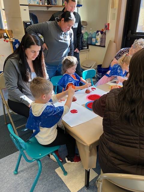 students and adults at a table making a craft