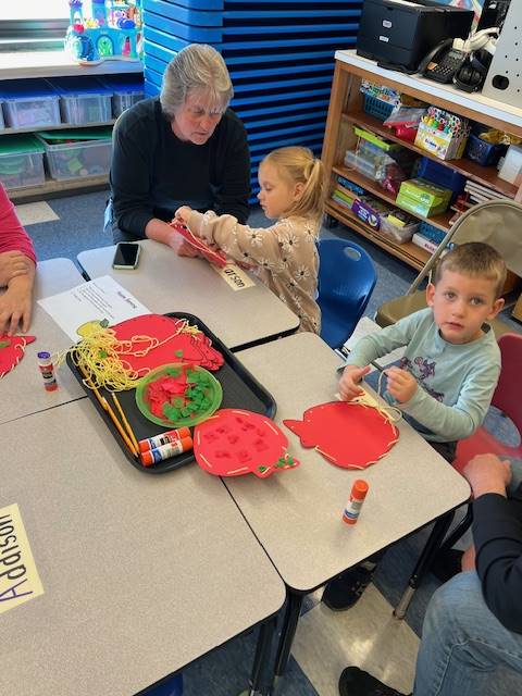 students with adult sewing a paper pumpkin