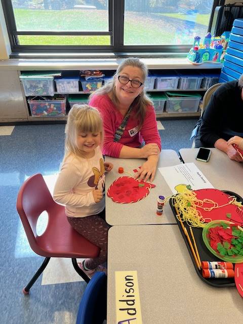 and adult and student making a paper pumpkin