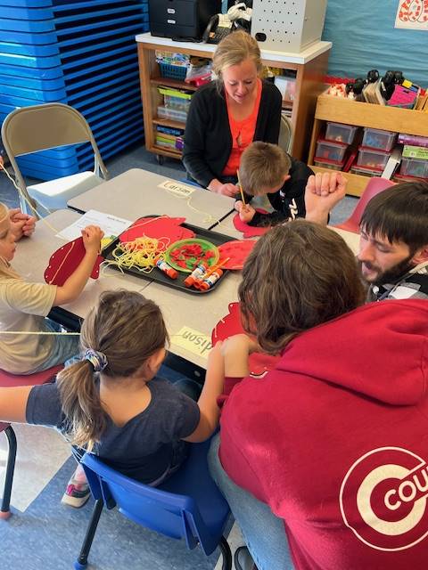 students with adult sewing a paper pumpkin