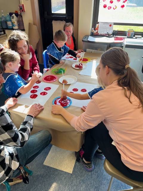 students painting with red paint.