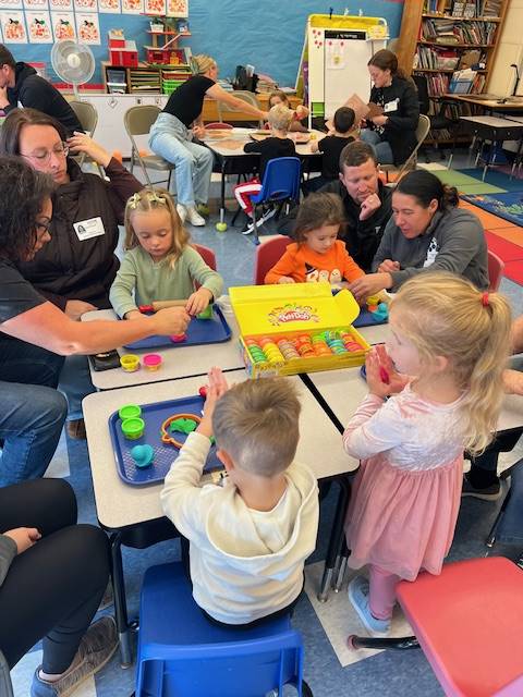 students at the desk playing with play do.