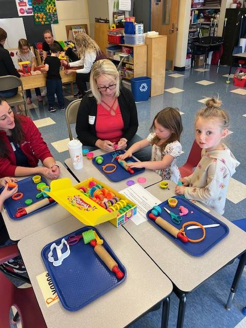 students at the desk playing with play do.