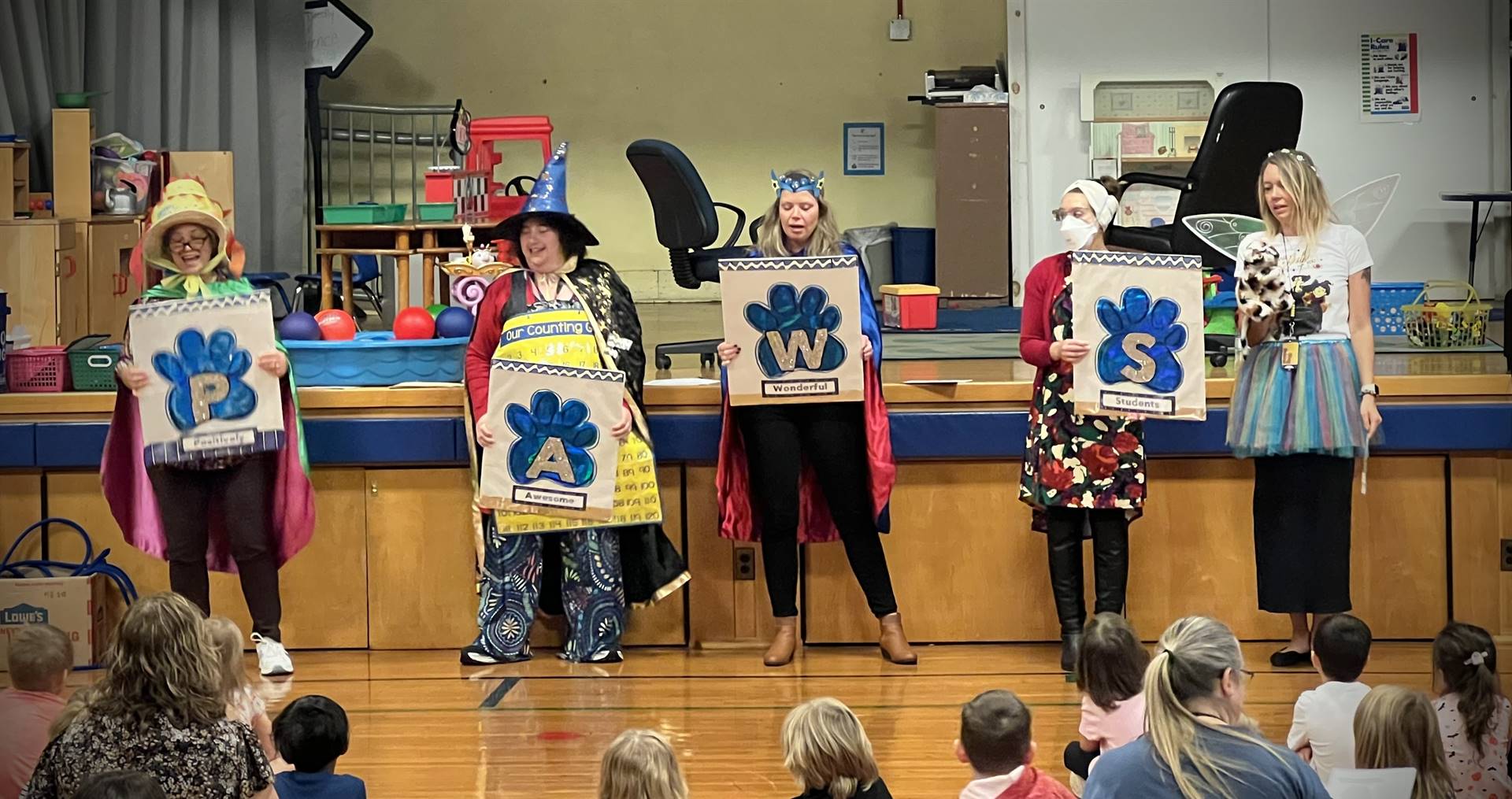 4 adults dressed as characters holding posters of blue paws.