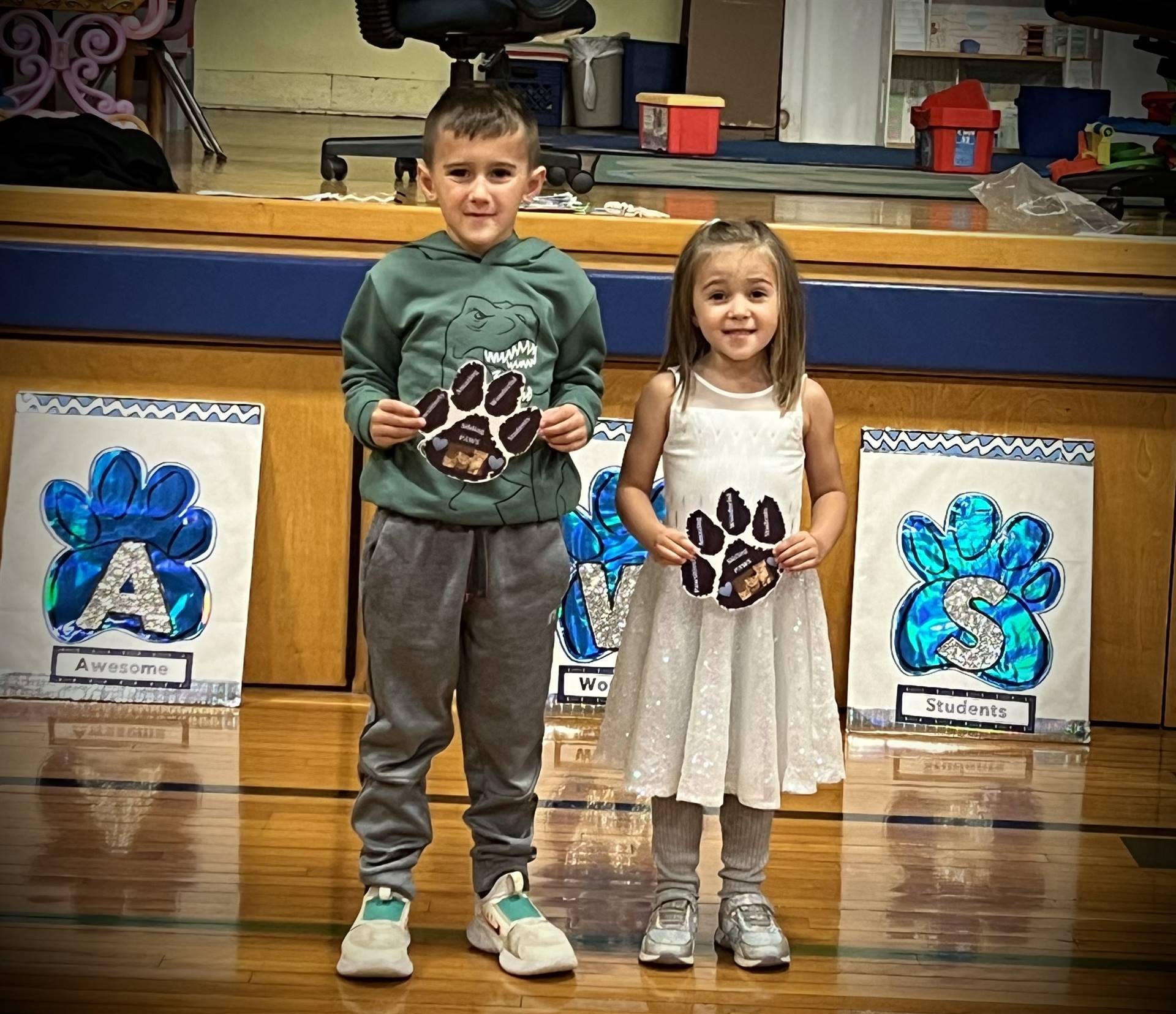 2 students holding a paper paw