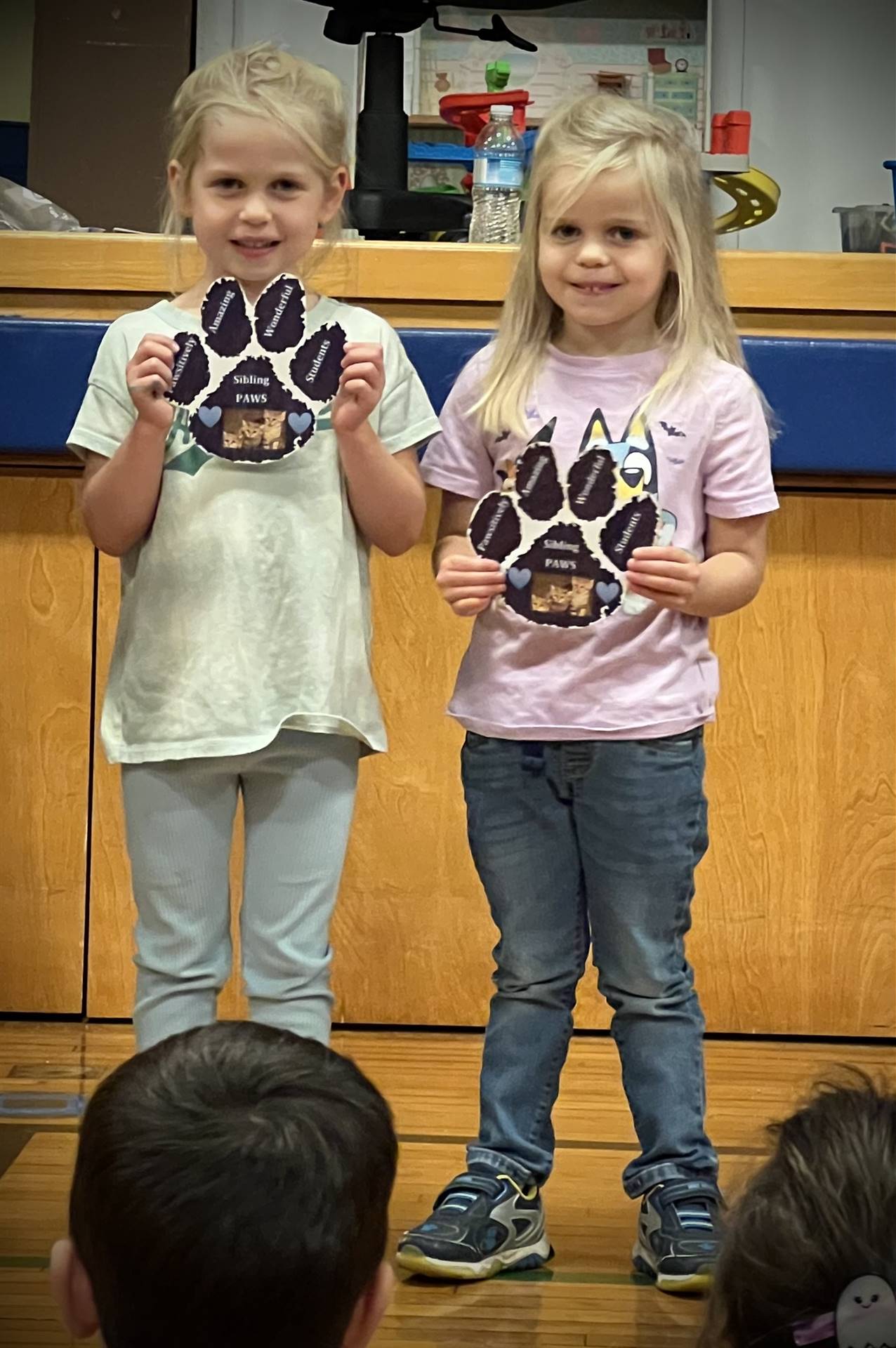 2 students holding a paper paw