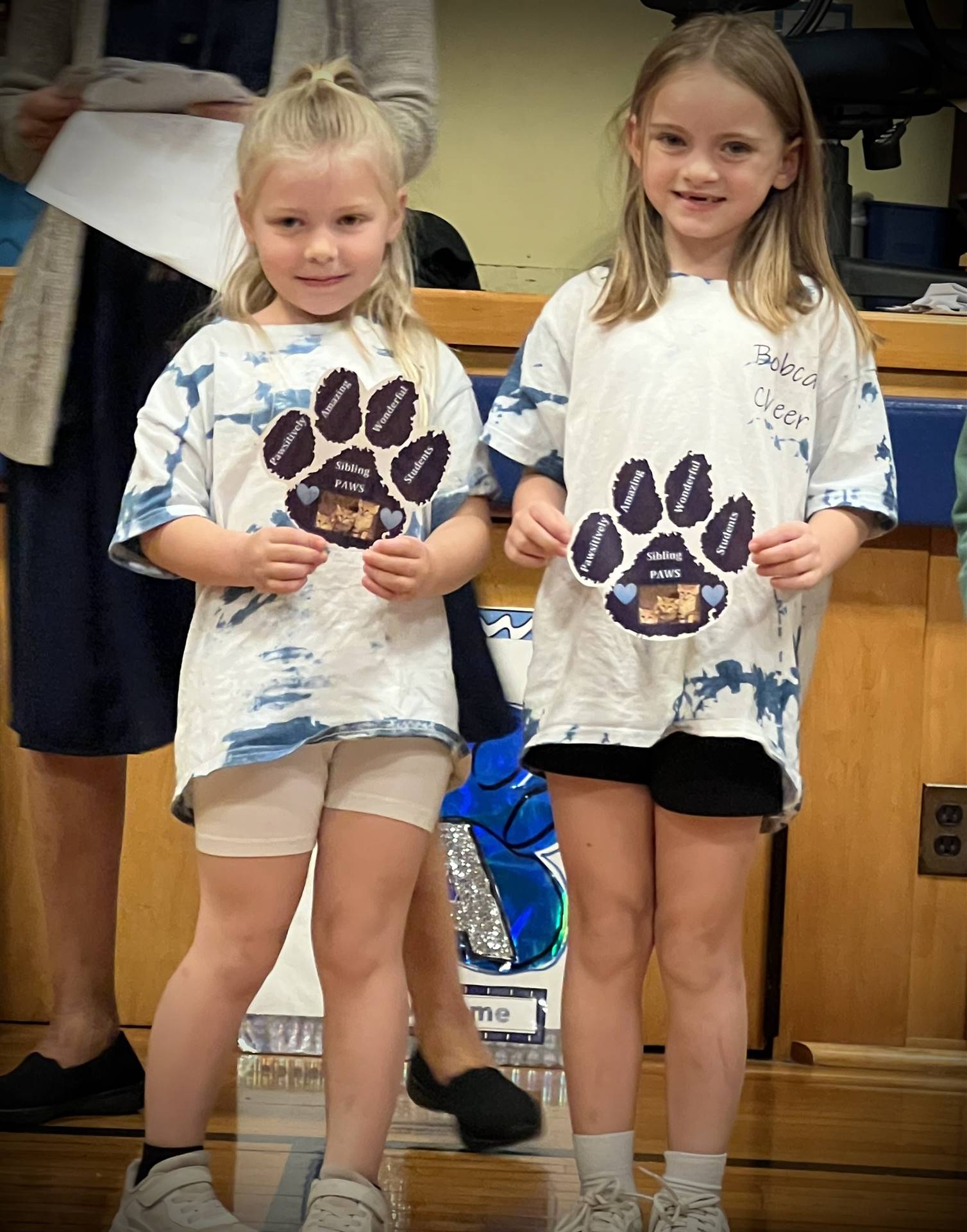 2 students holding a paper paw