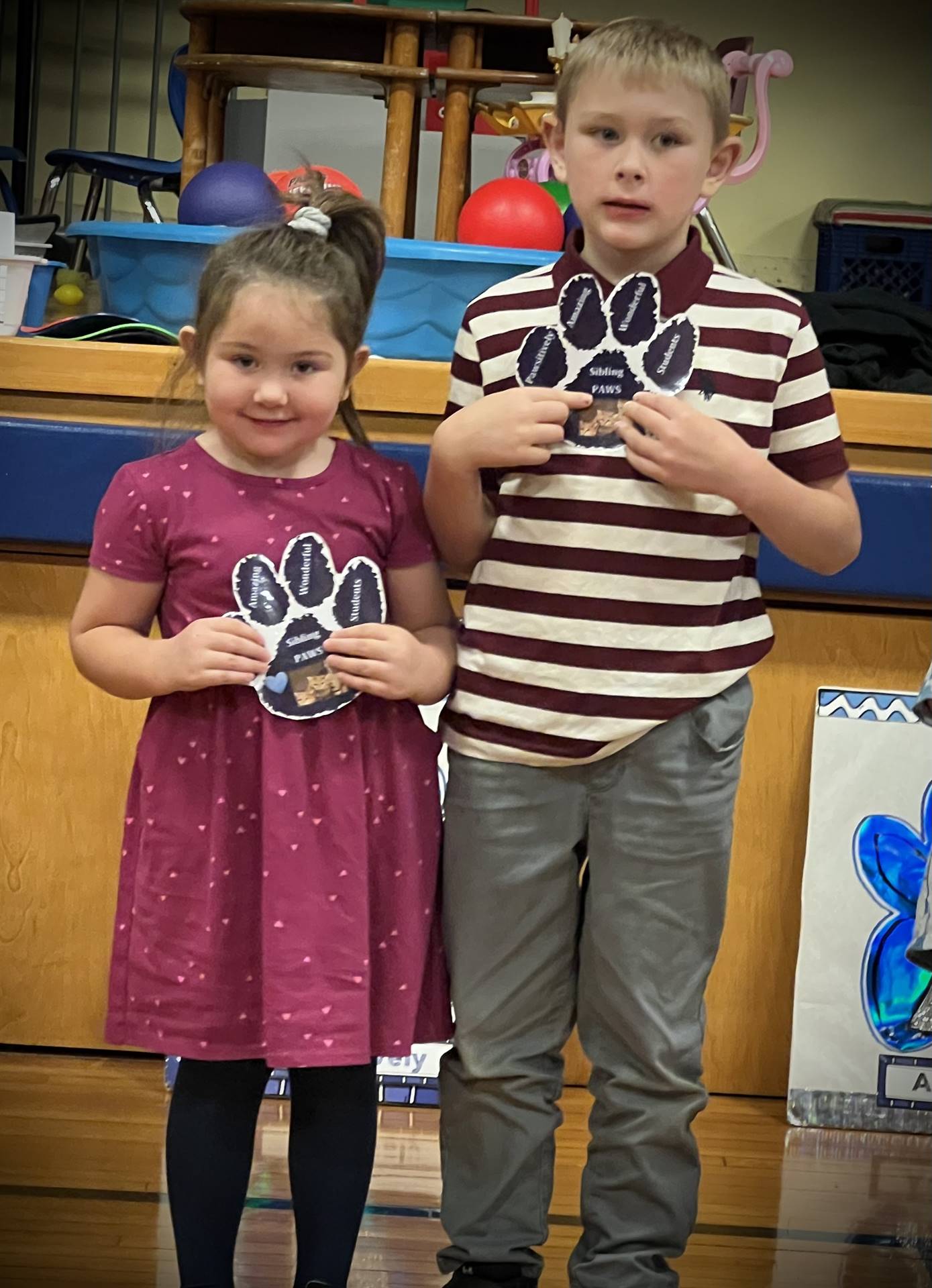 2 students holding a paper paw