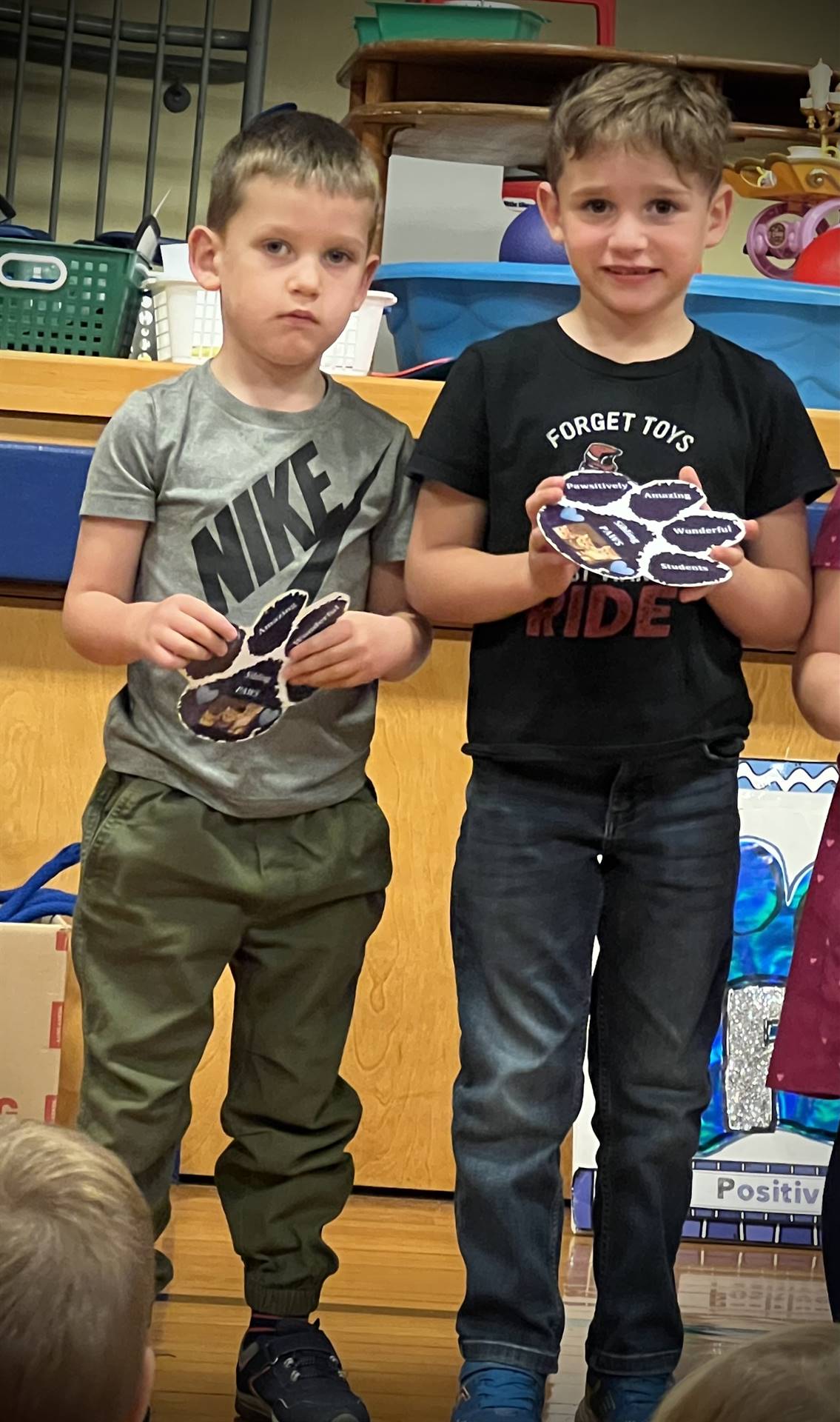 2 students holding a paper paw
