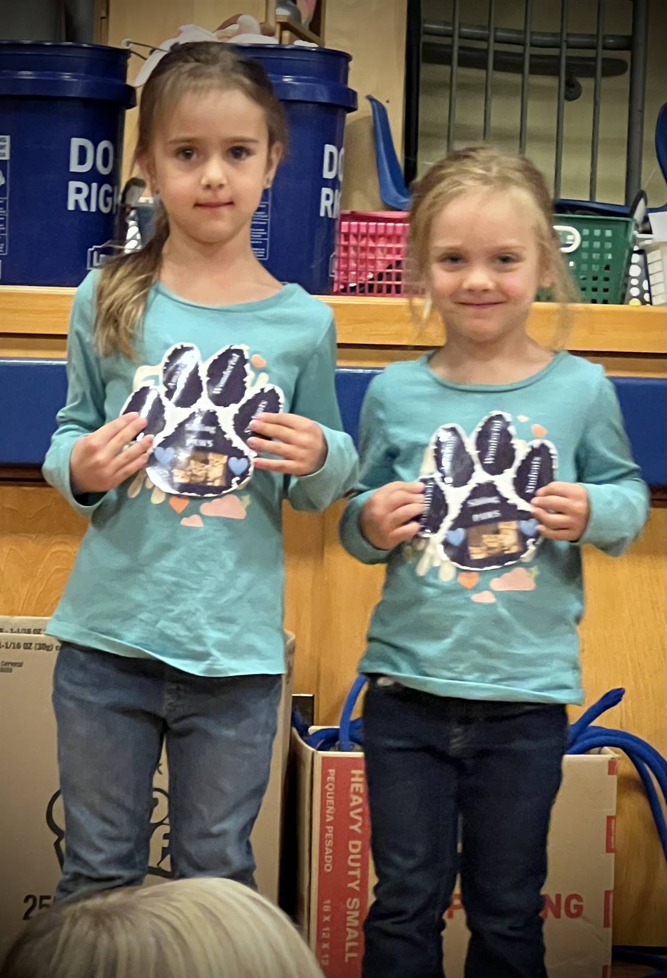 2 students holding a paper paw