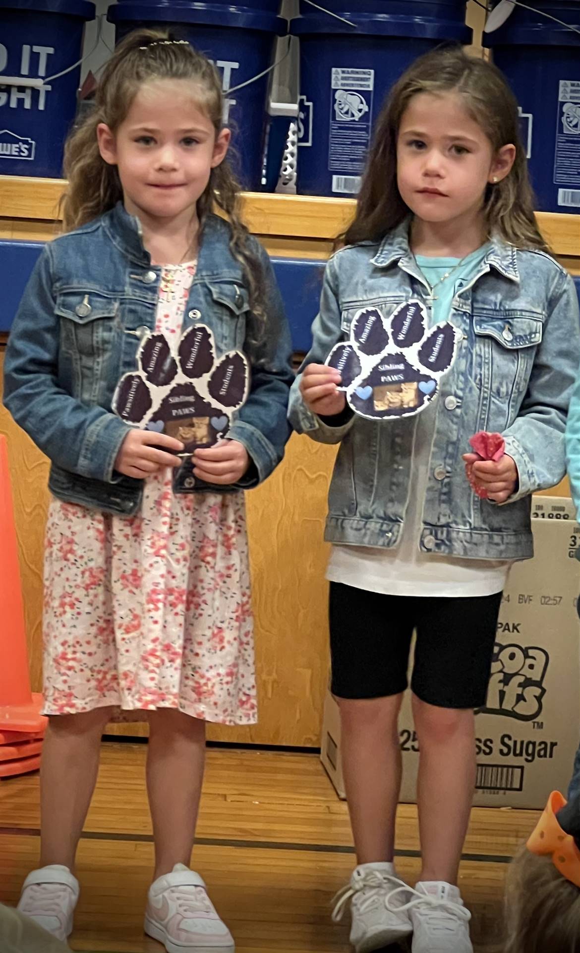 2 students holding a paper paw