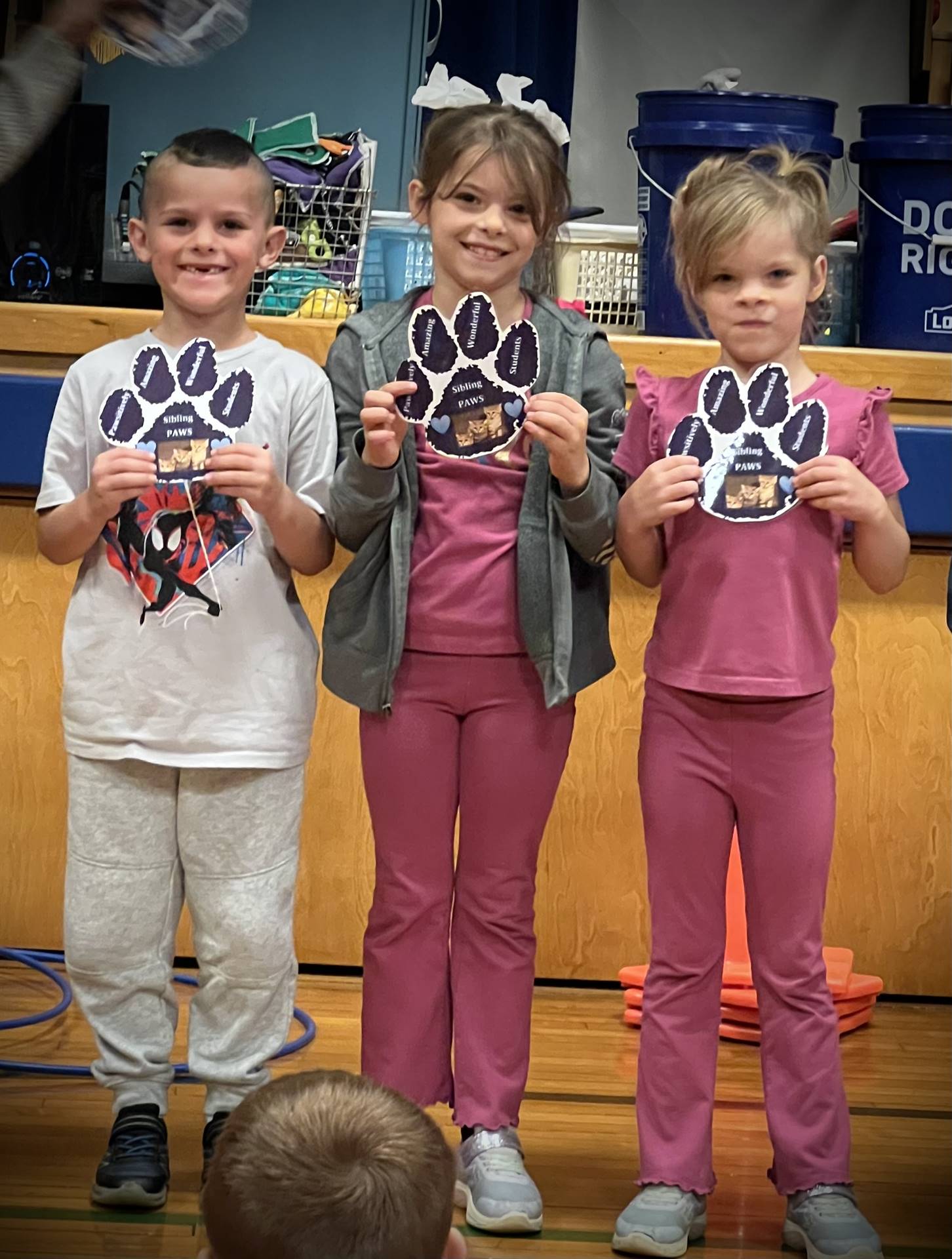 3 students holding  paper paws