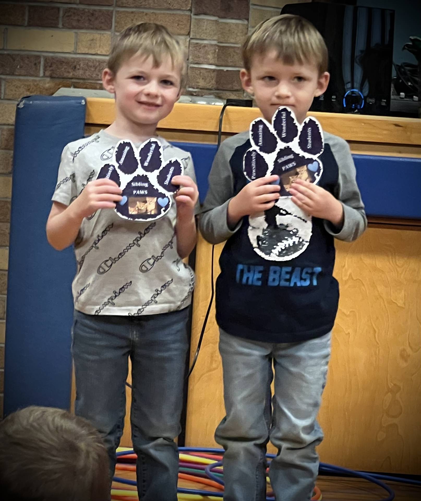 2 students holding a paper paw