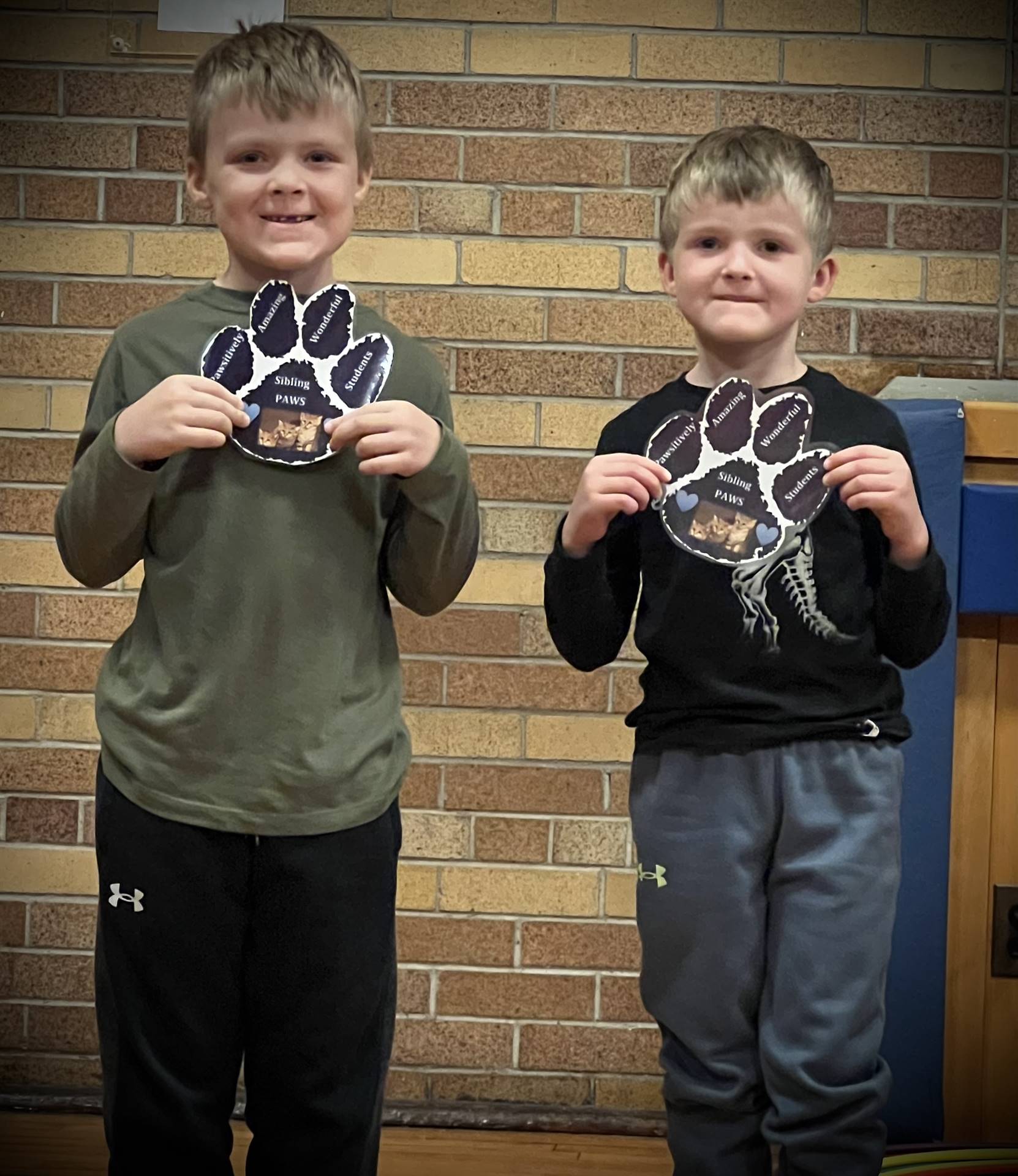 2 students holding a paper paw