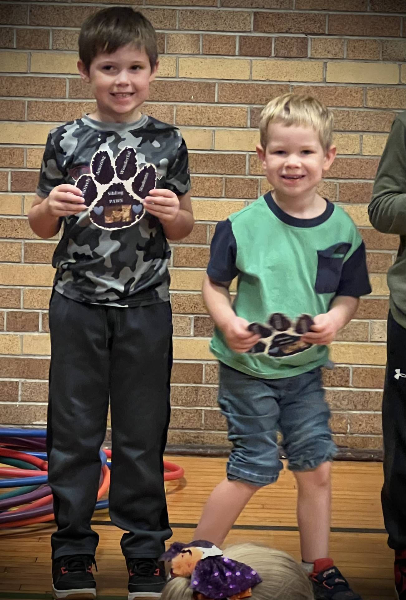 2 students holding a paper paw