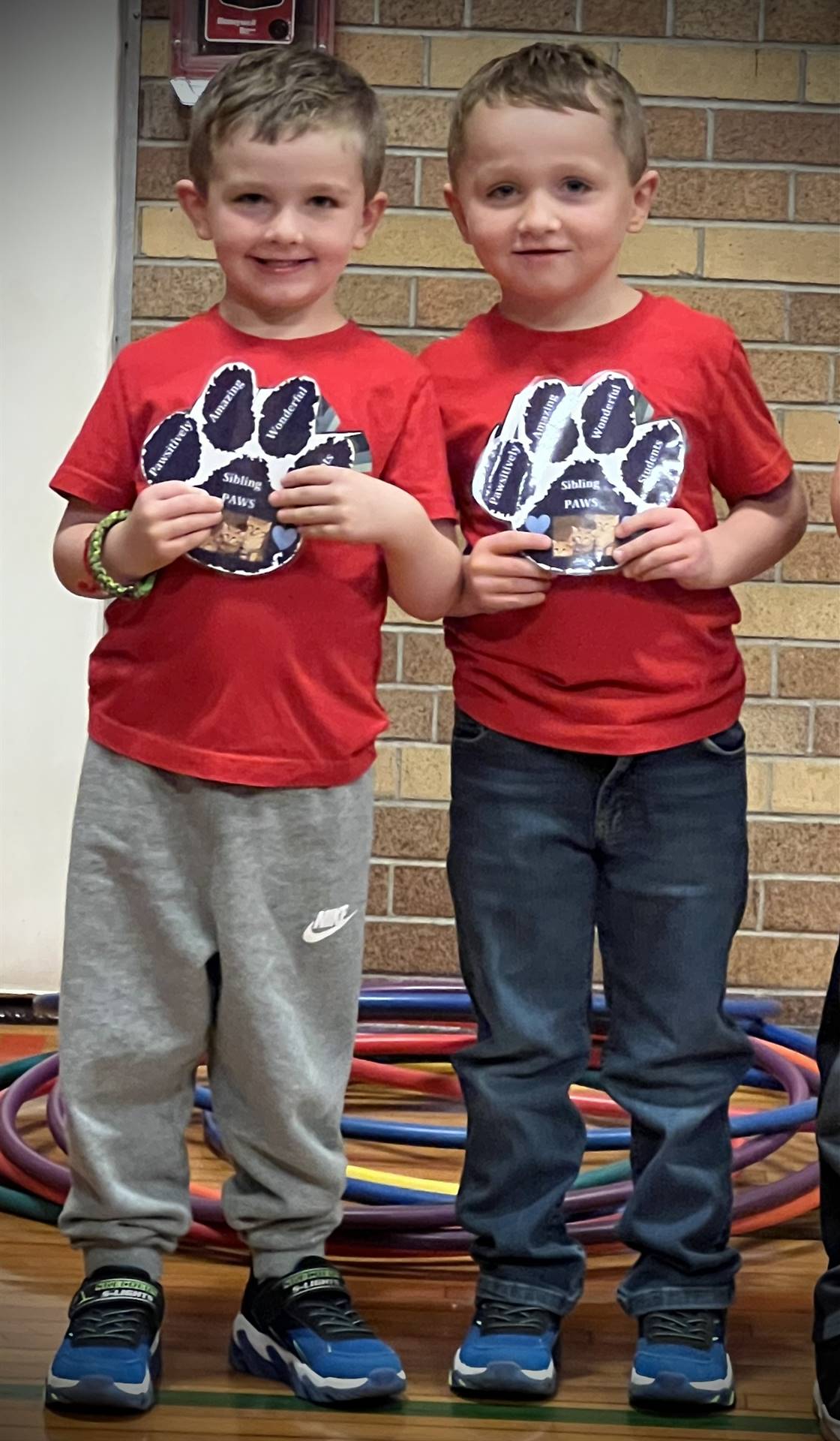 2 students holding a paper paw