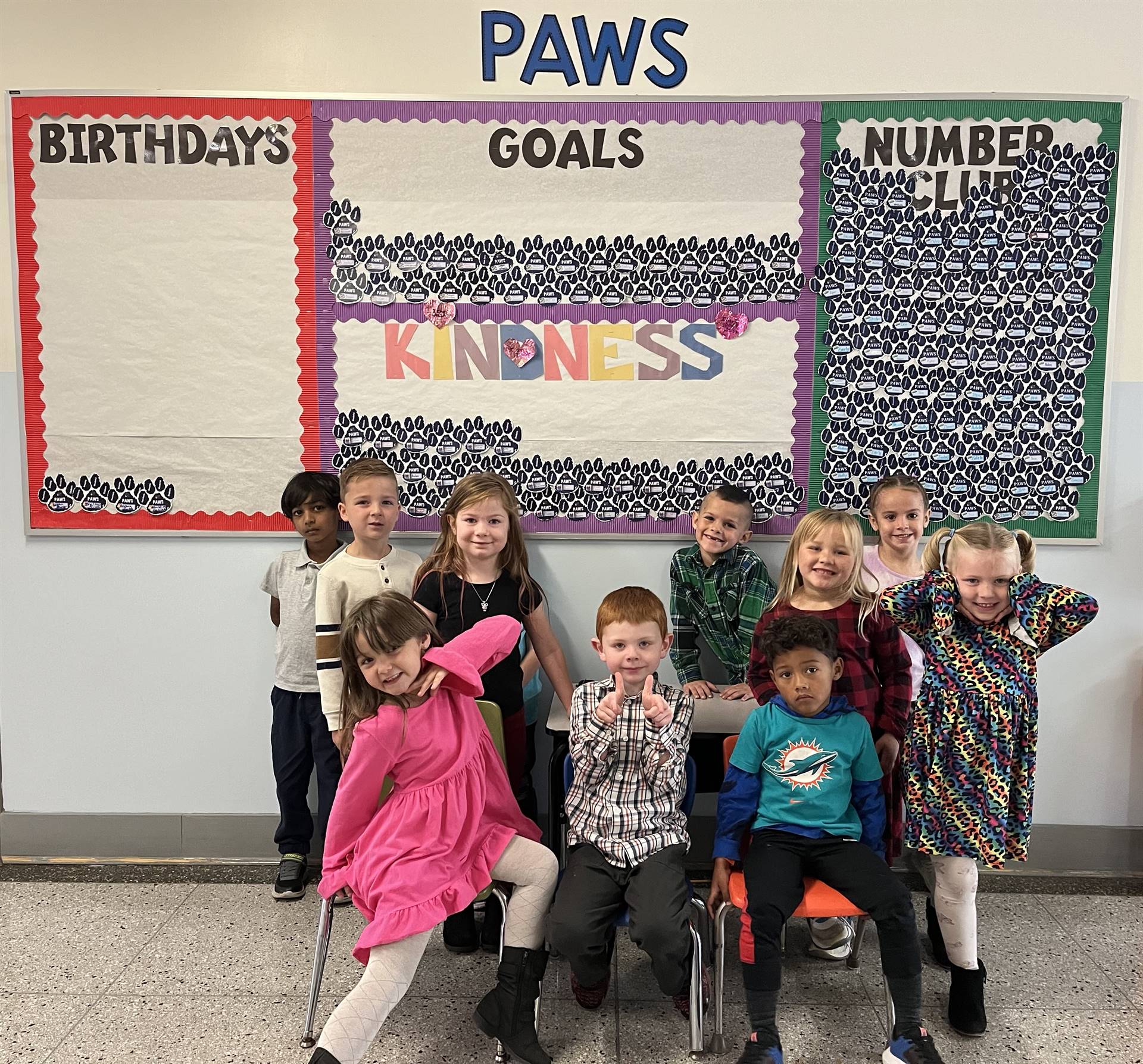 students pose in front of the October PAWS bulletin board!