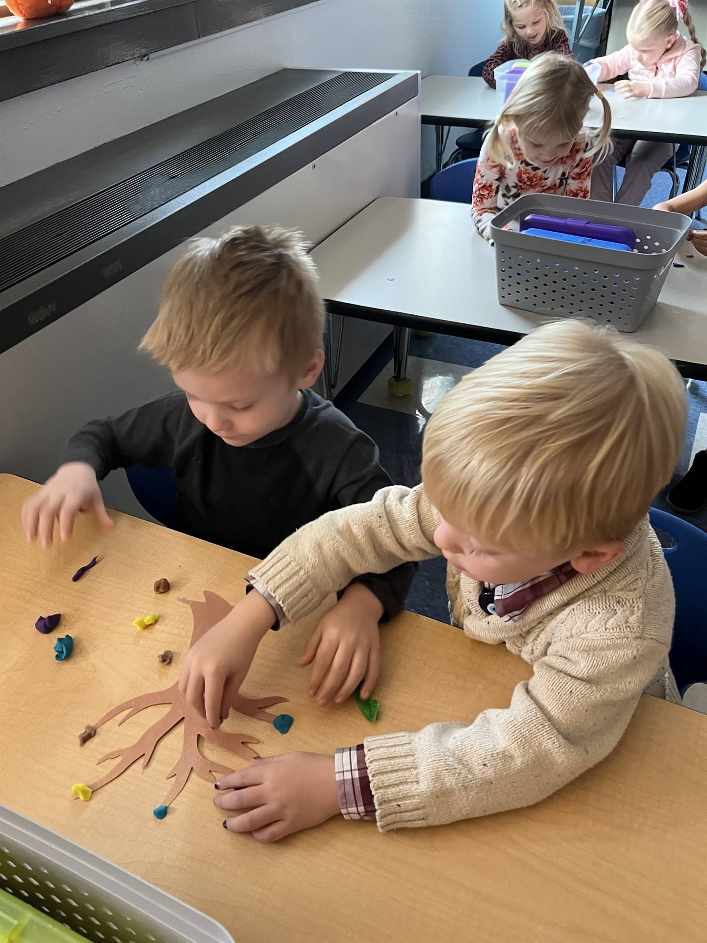 2 students using play do to create leaves for a bare fall tree