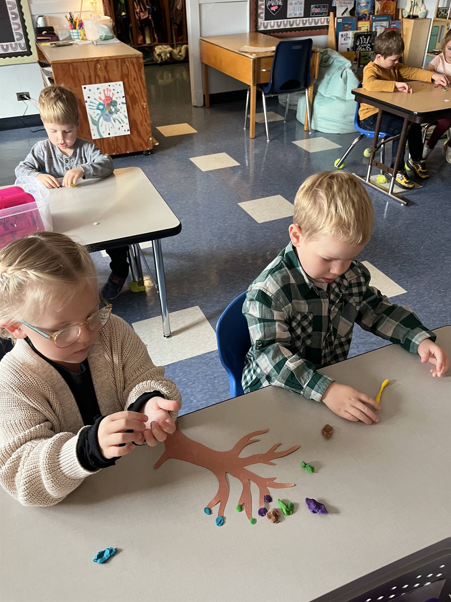 2 students using play do to create leaves for a bare fall tree