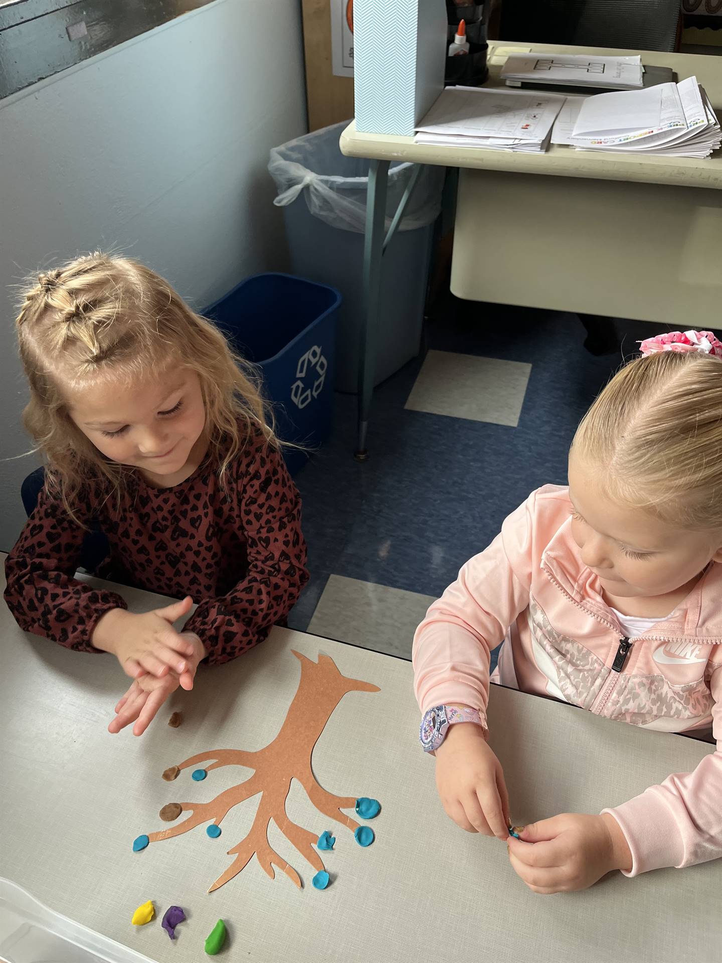 2 students using play do to create leaves for a bare fall tree