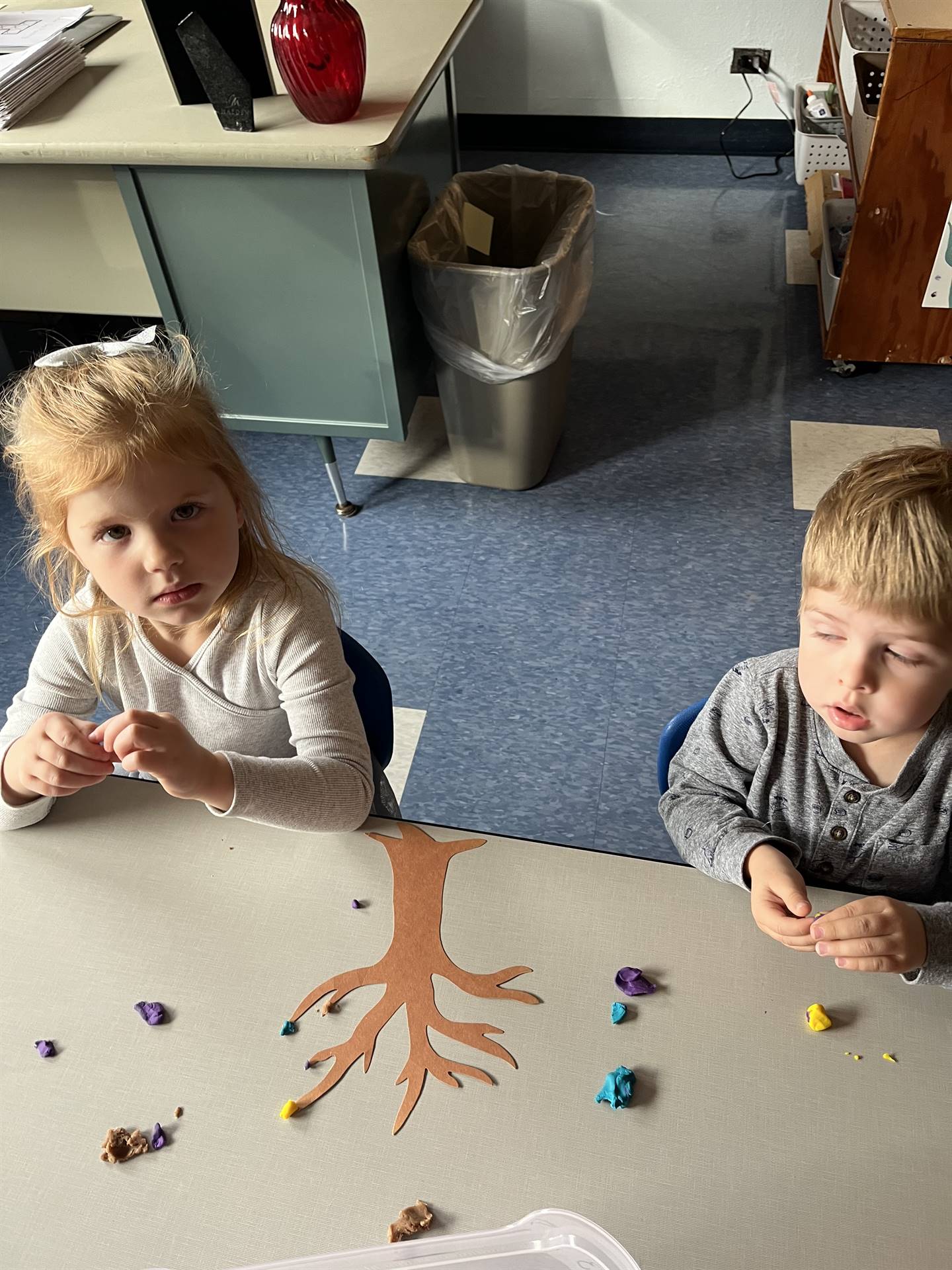 2 students using play do to create leaves for a bare fall tree
