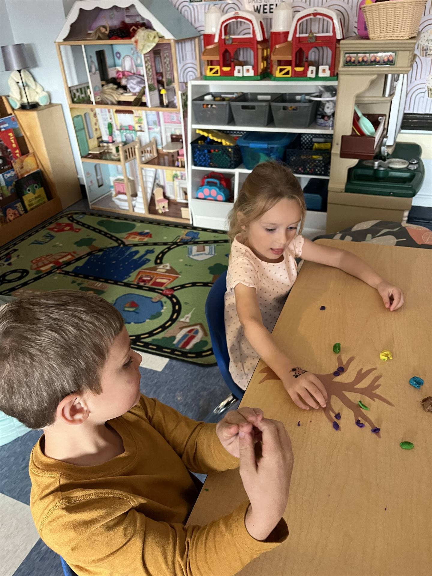 2 students using play do to create leaves for a bare fall tree