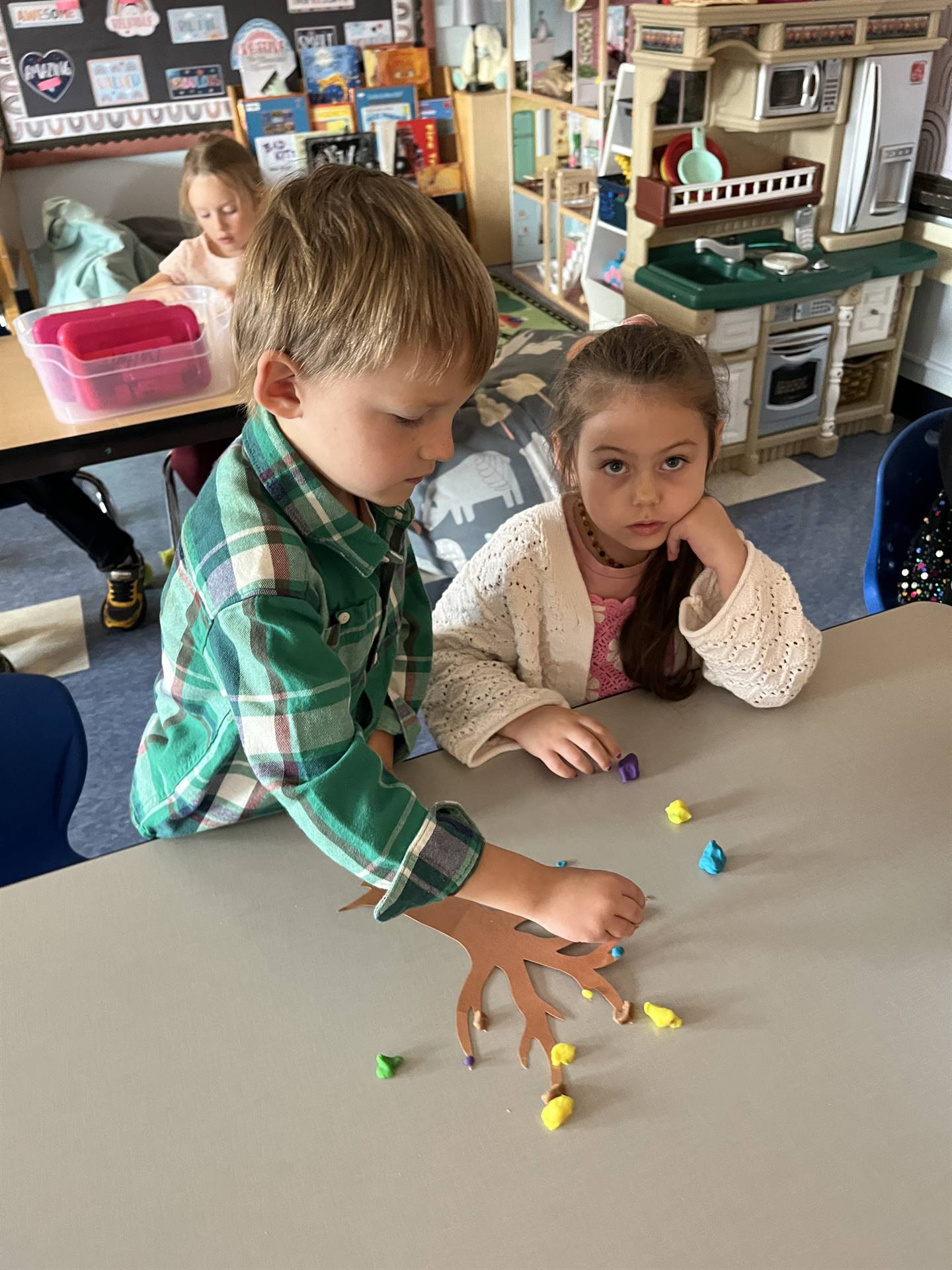 2 students using play do to create leaves for a bare fall tree