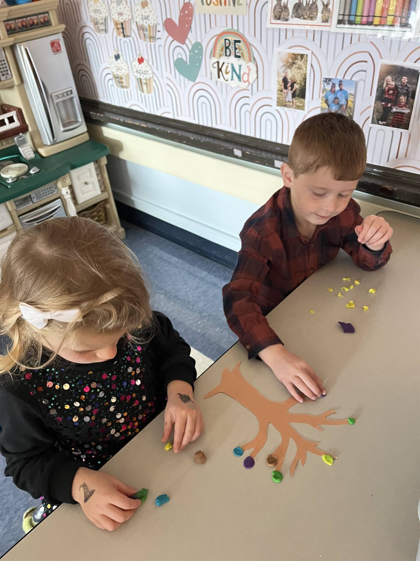 2 students using play do to create leaves for a bare fall tree