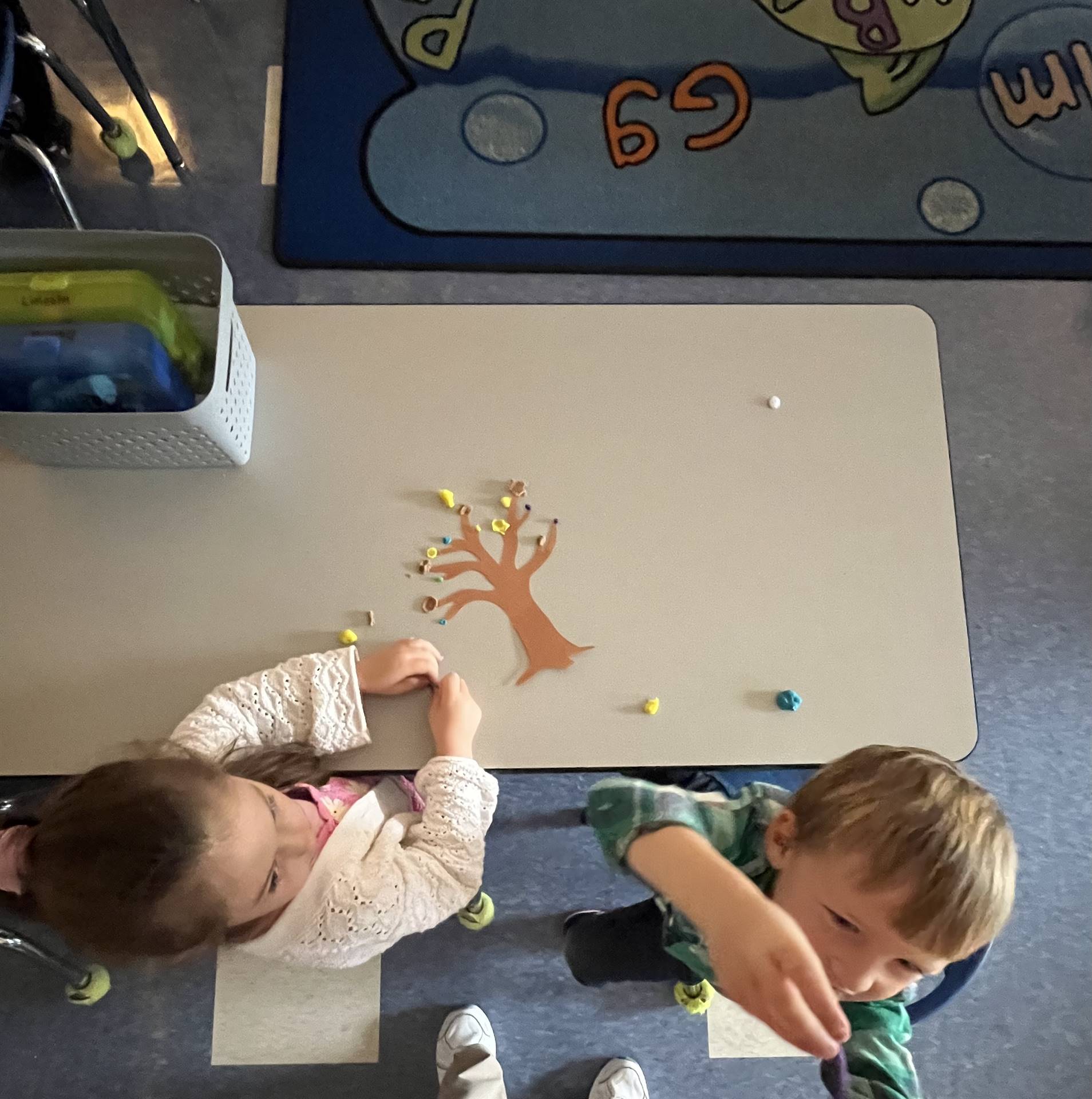 2 students using play do to create leaves for a bare fall tree