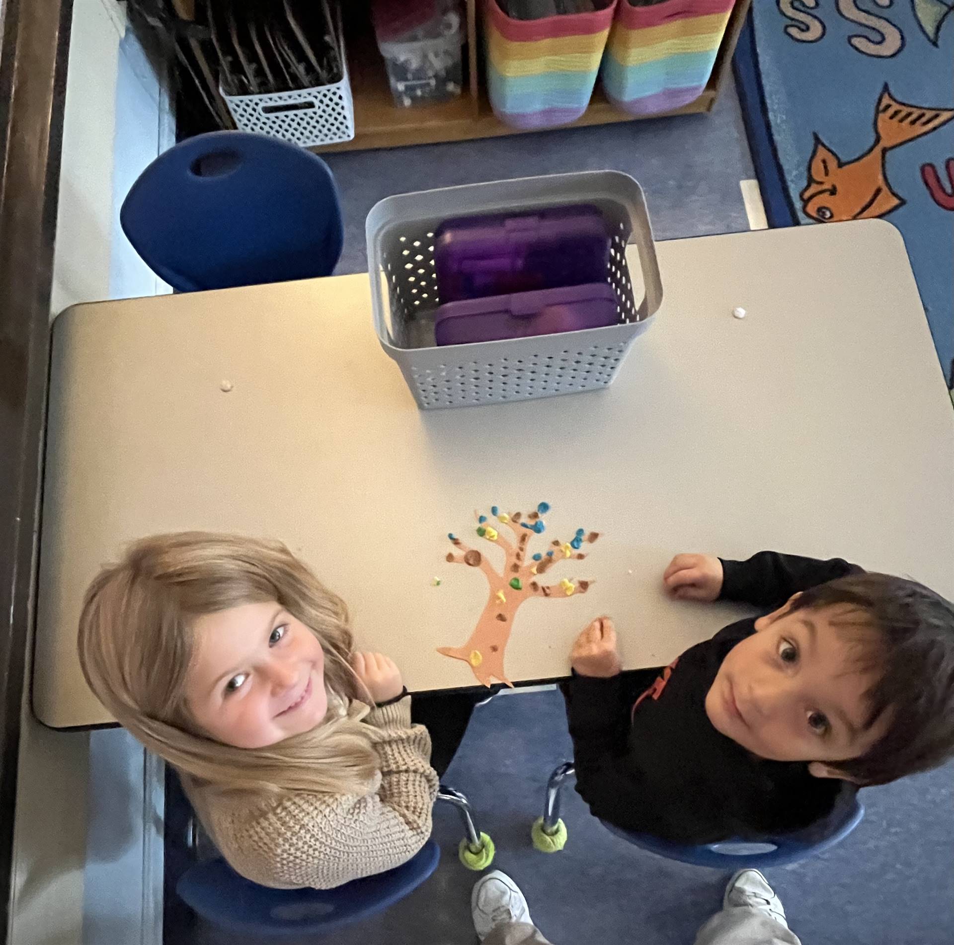 2 students using play do to create leaves for a bare fall tree
