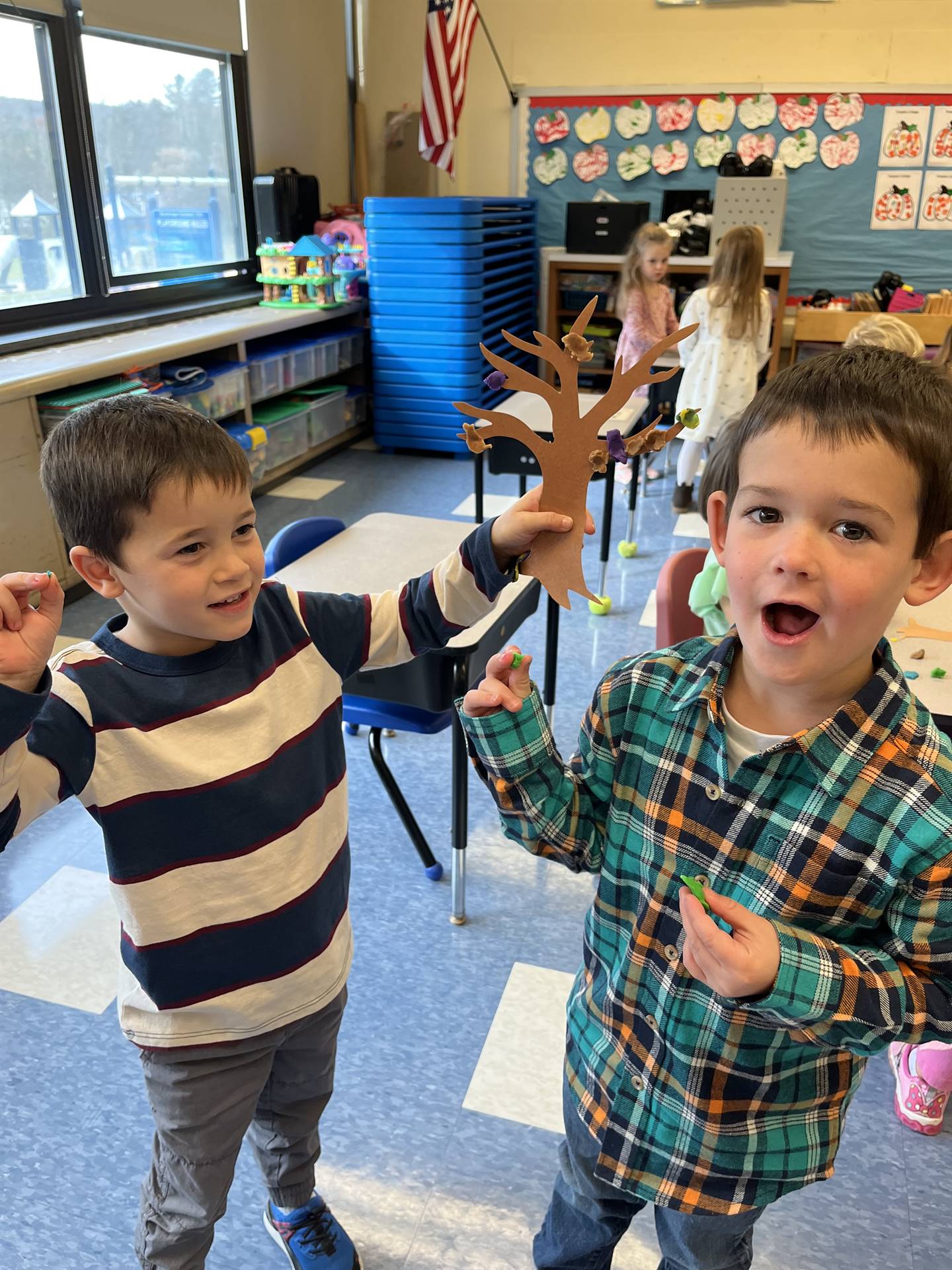 2 students using play do to create leaves for a bare fall tree
