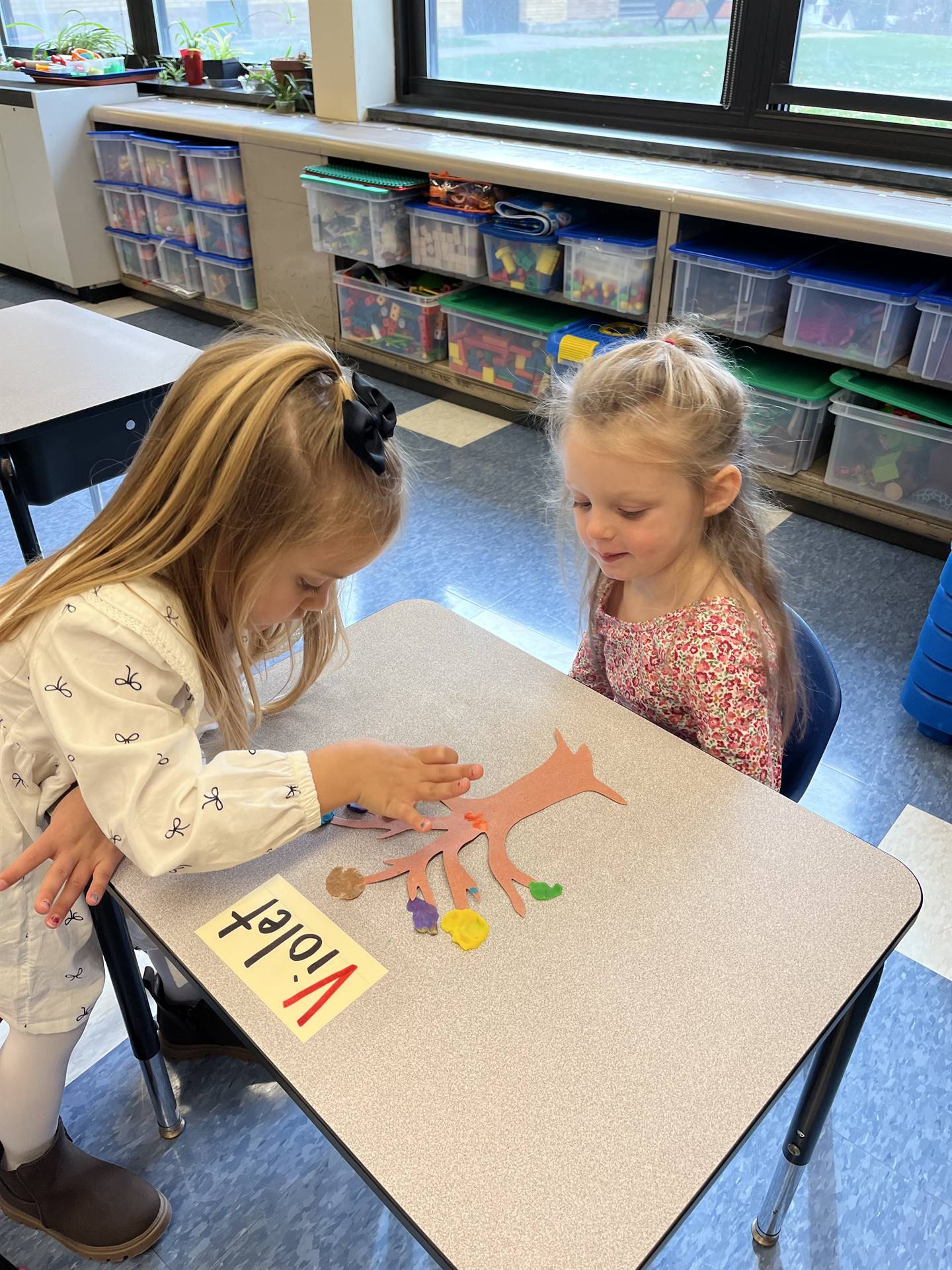 2 students using play do to create leaves for a bare fall tree