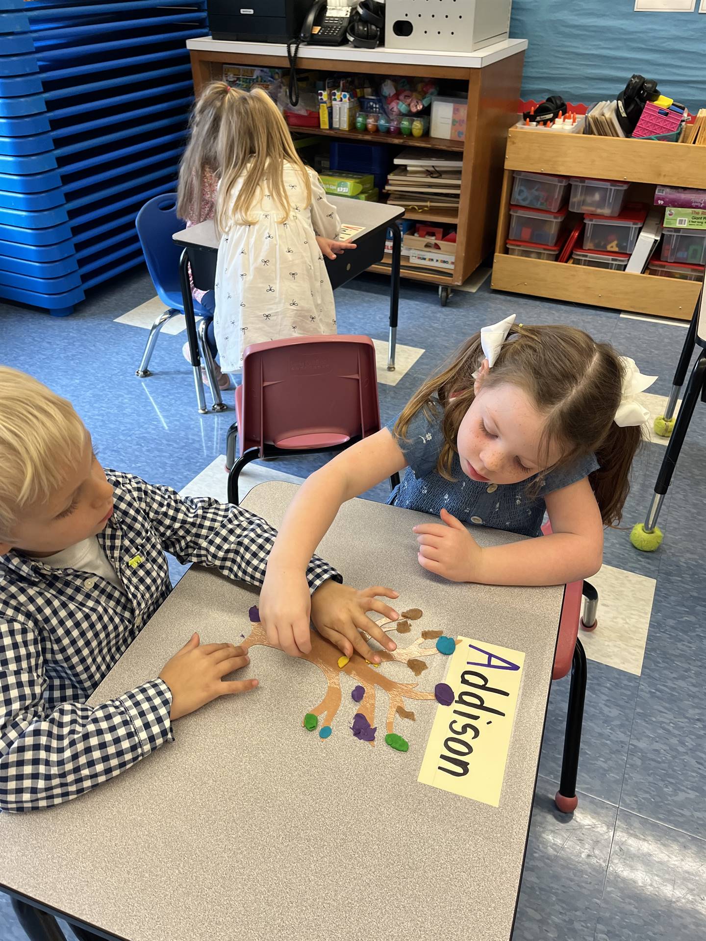 2 students using play do to create leaves for a bare fall tree
