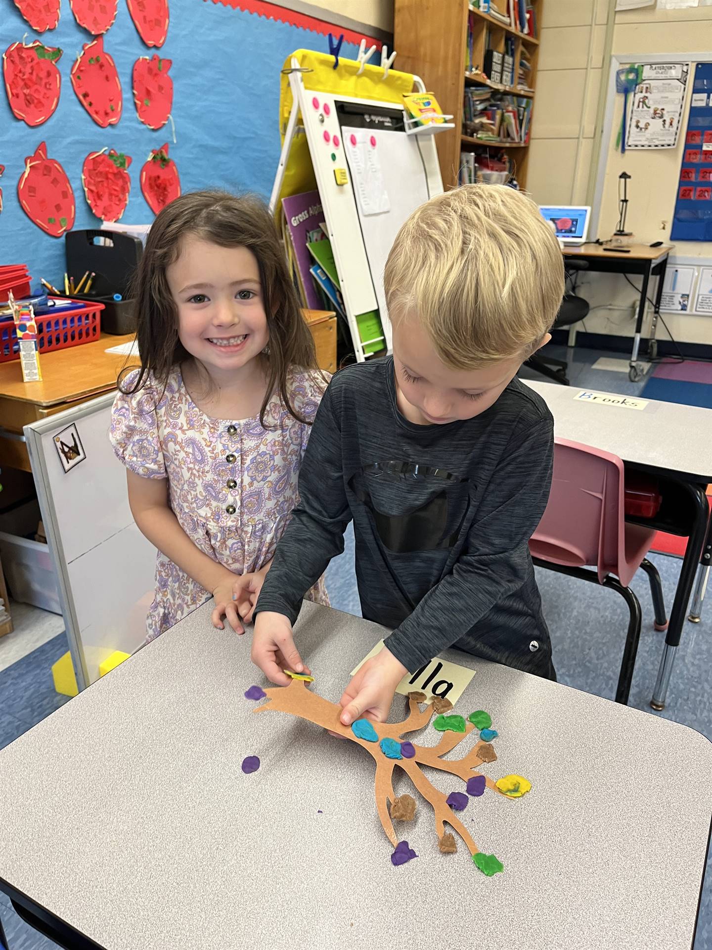 2 students using play do to create leaves for a bare fall tree