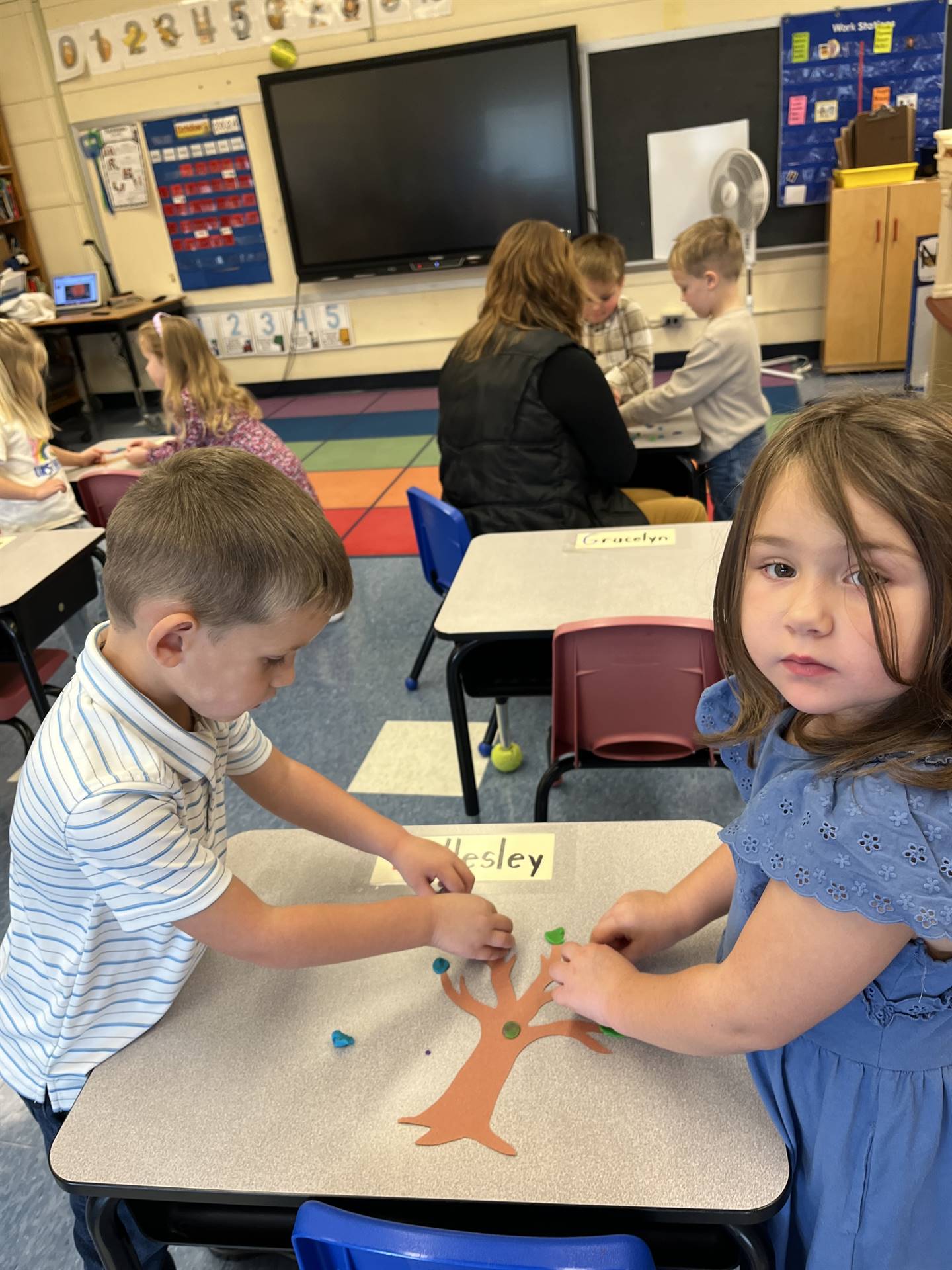 2 students using play do to create leaves for a bare fall tree