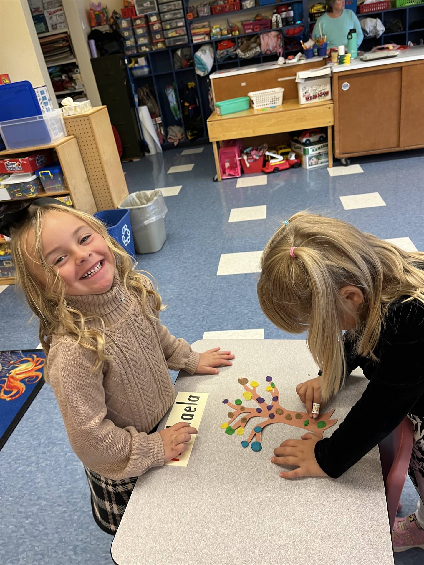 2 students using play do to create leaves for a bare fall tree